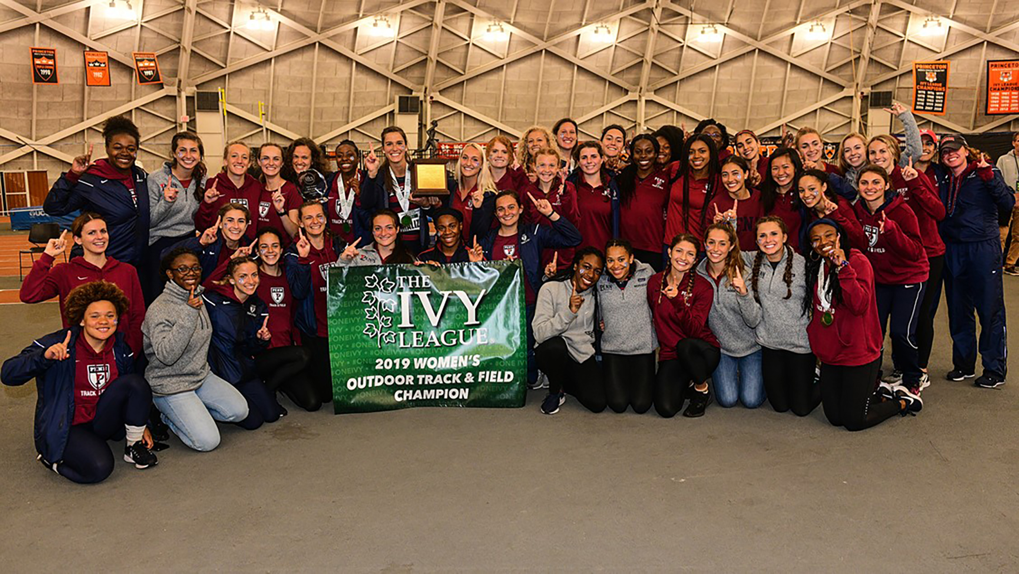 Members of the women's track and field team pose with the 2019 Outdoor Ivy Heps championship banner.