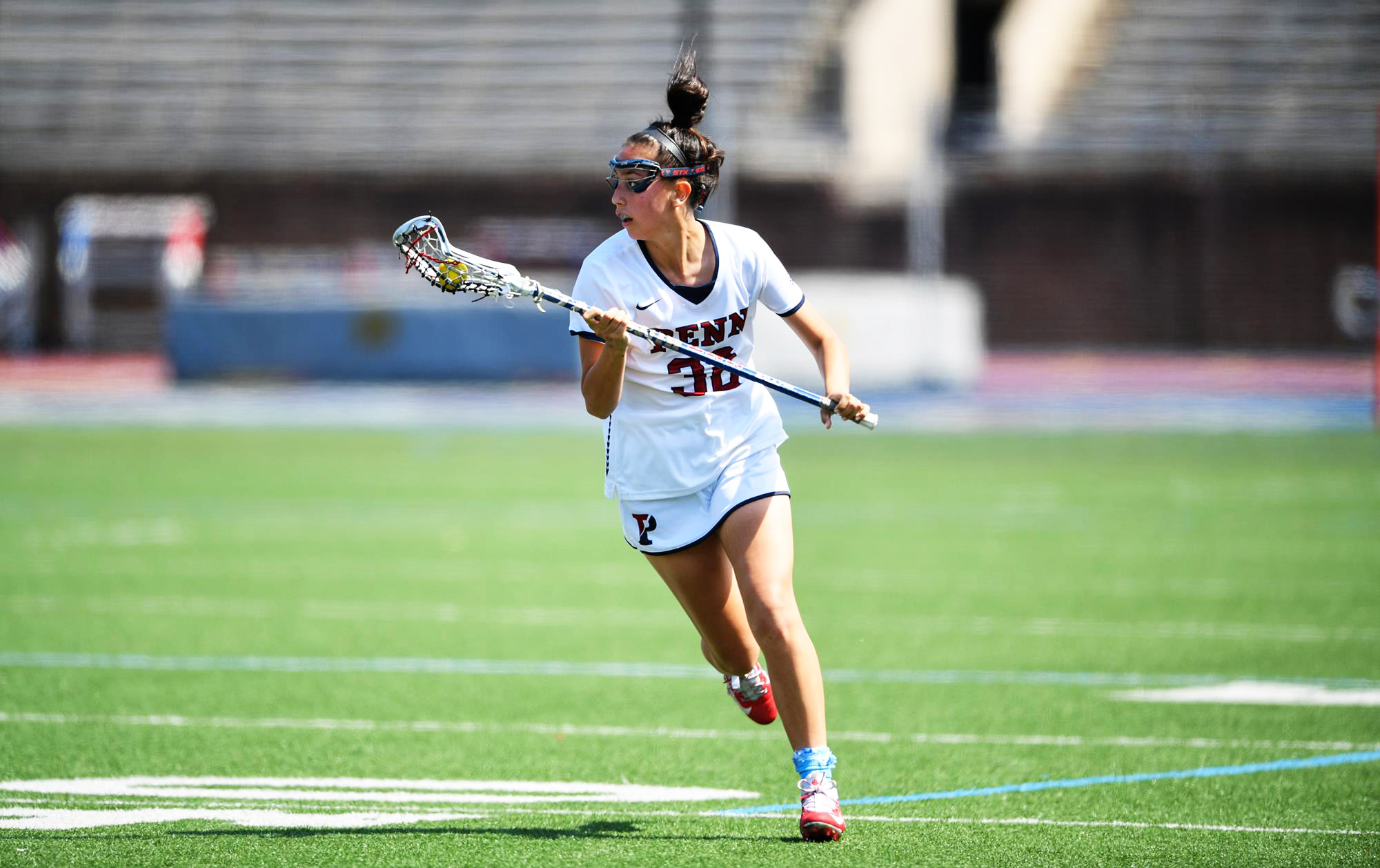 Michaela McMahon of the women's lacrosse runs up the field holding her stick.