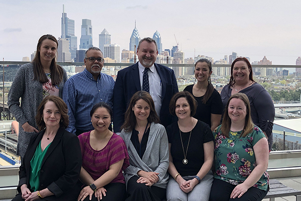 Team portrait of OncoLink staff on a rooftop with Philadelphia skyline in background
