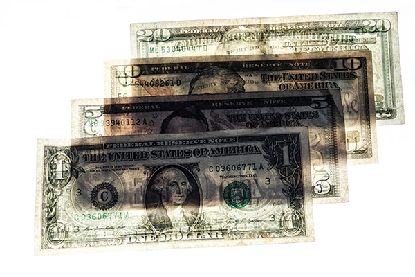Four semi-transparent paper U.S. bills fanned out flat.