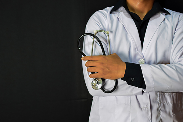 torso of doctor with crossed arms in white lab coat holding a stethoscope