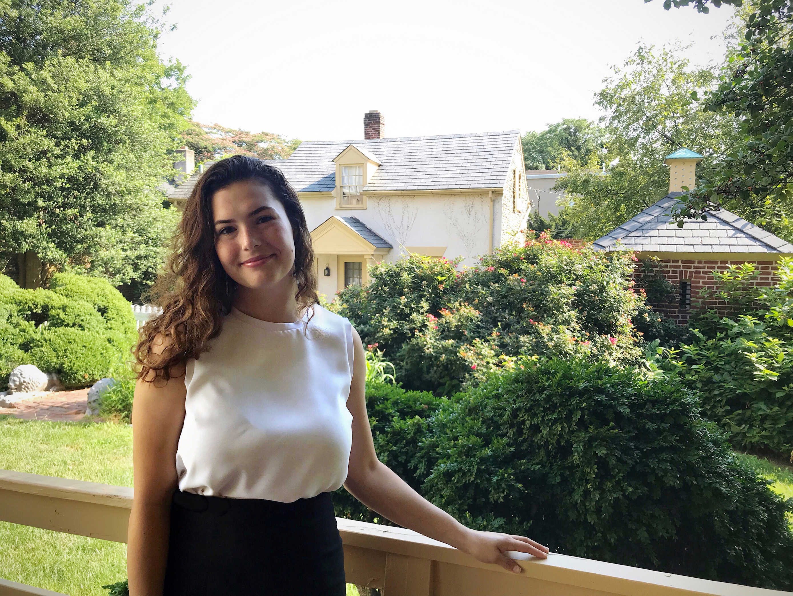 Student standing with historic buildings behind her. 