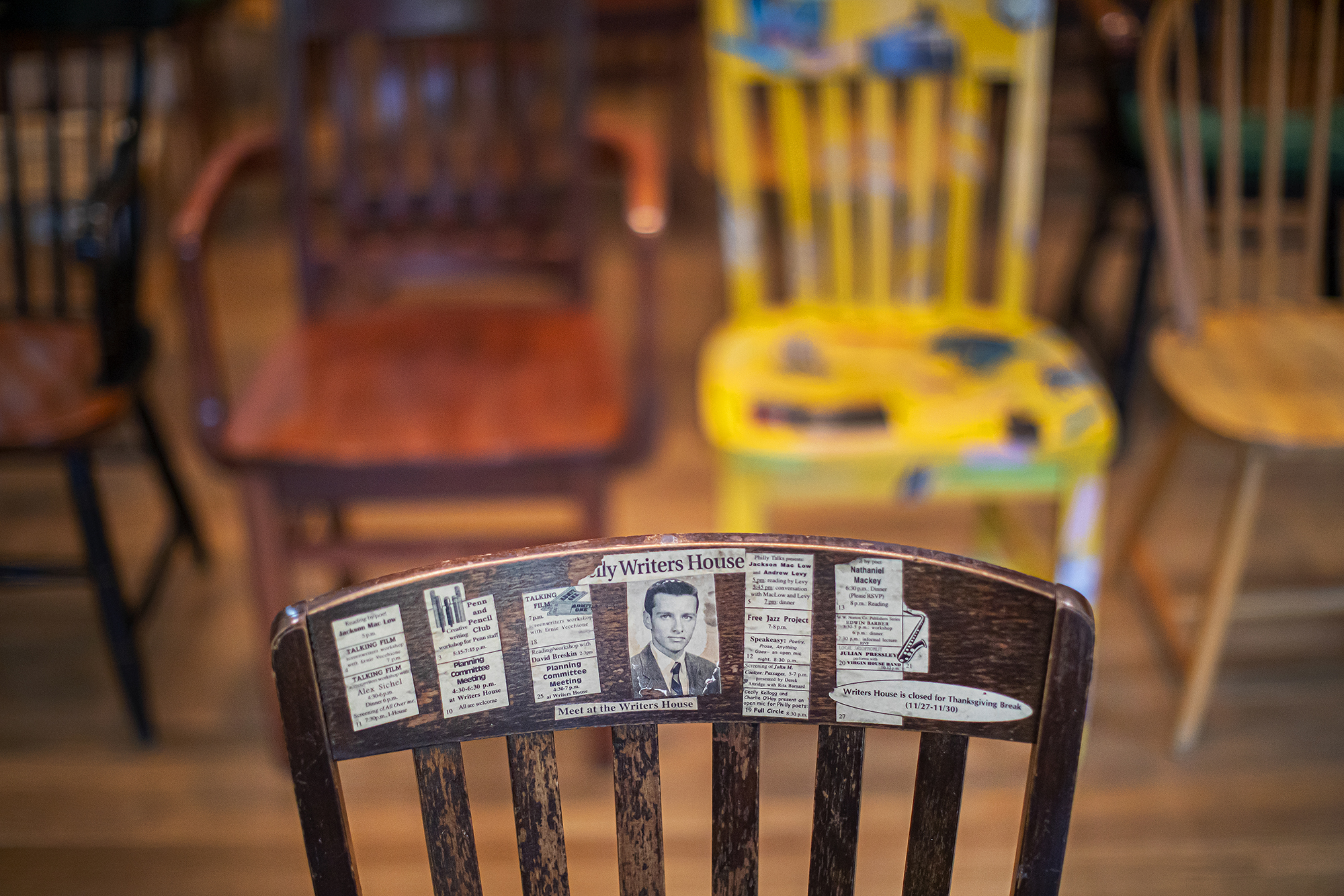 Top of the back of a wooden chair with newspaper articles and photos pasted on.