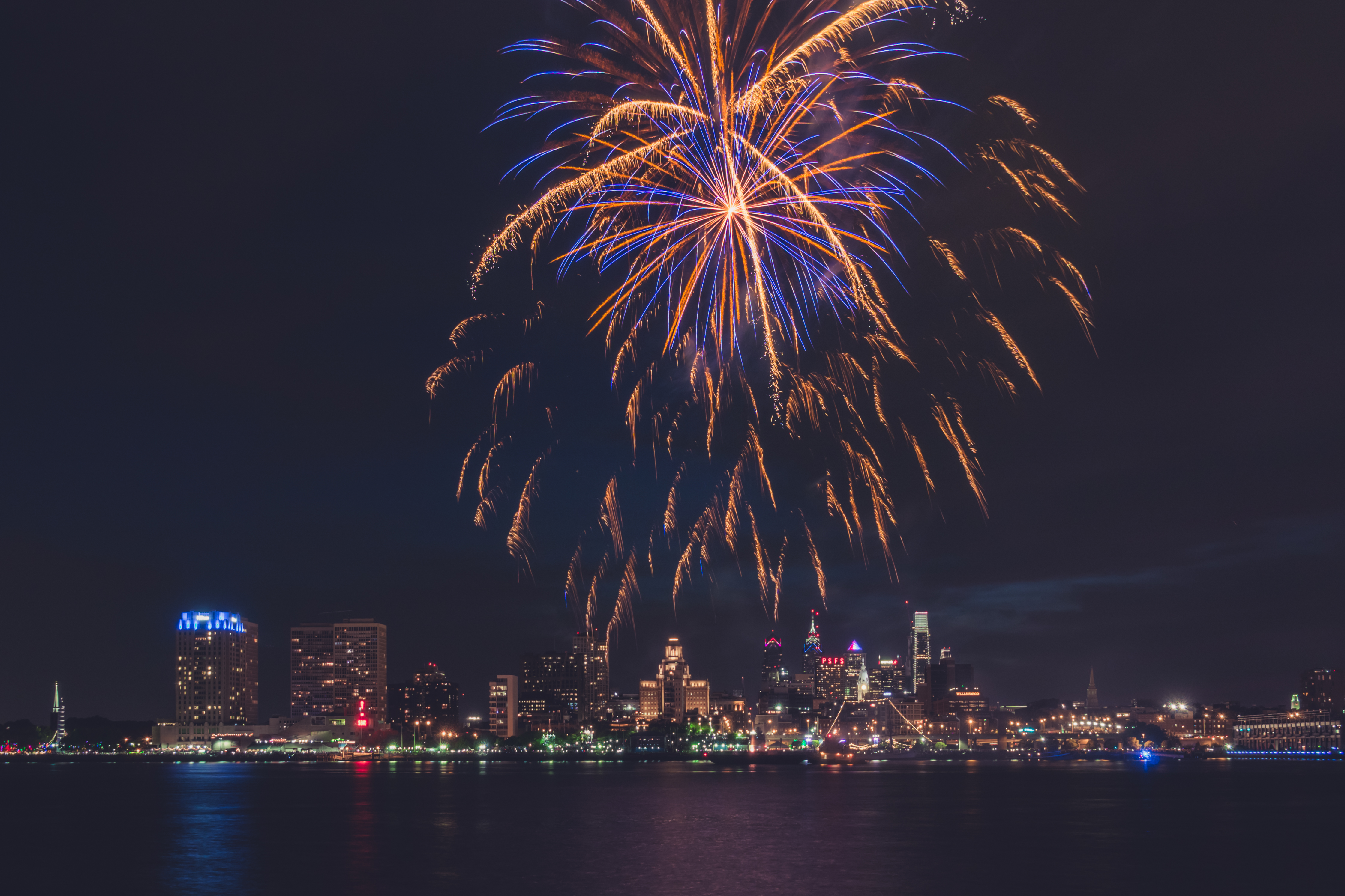 a massive blue an orange firework exploding over the Philadelphia skyline