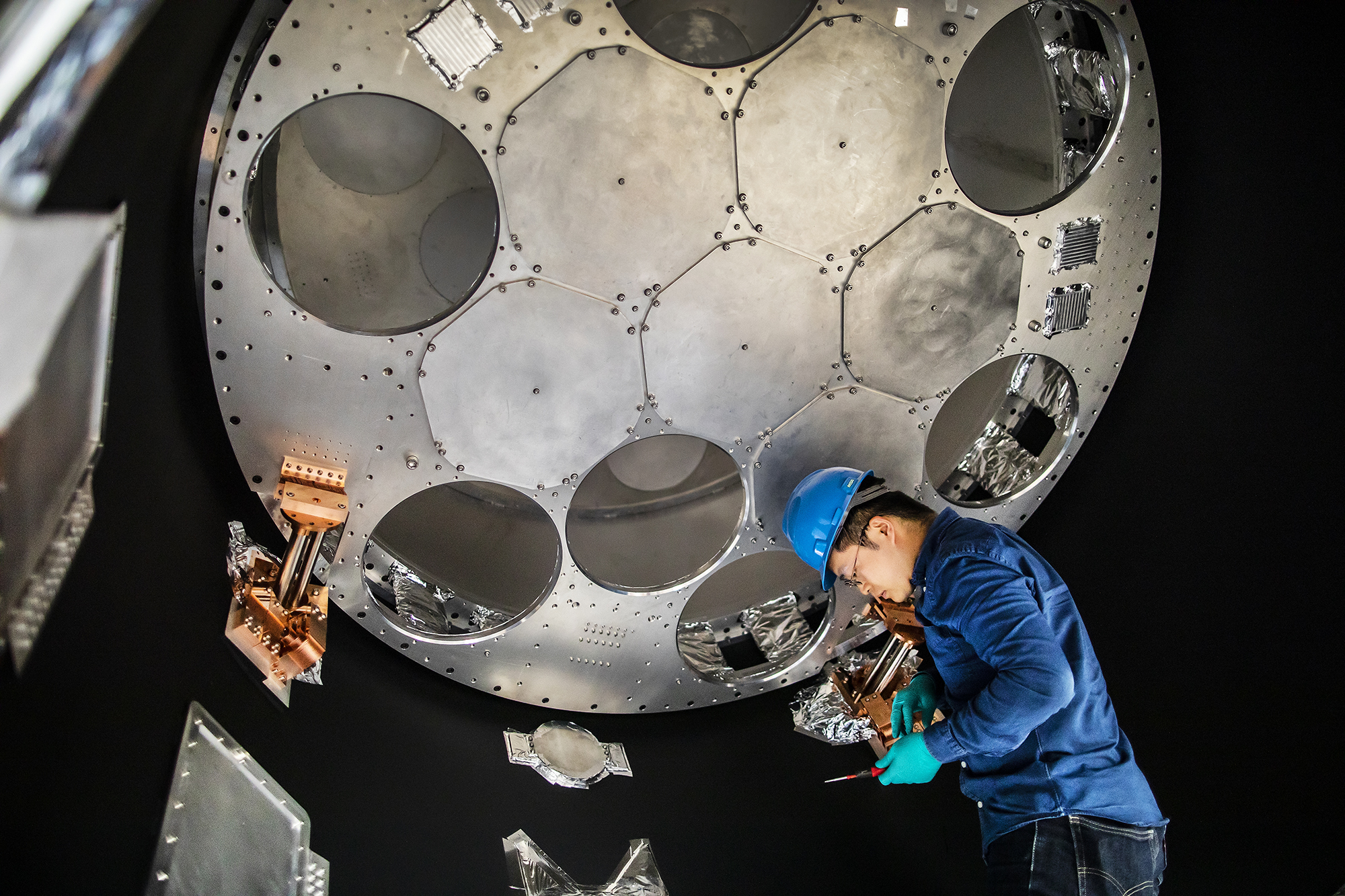 a person in a hard had working inside a large telescope detector