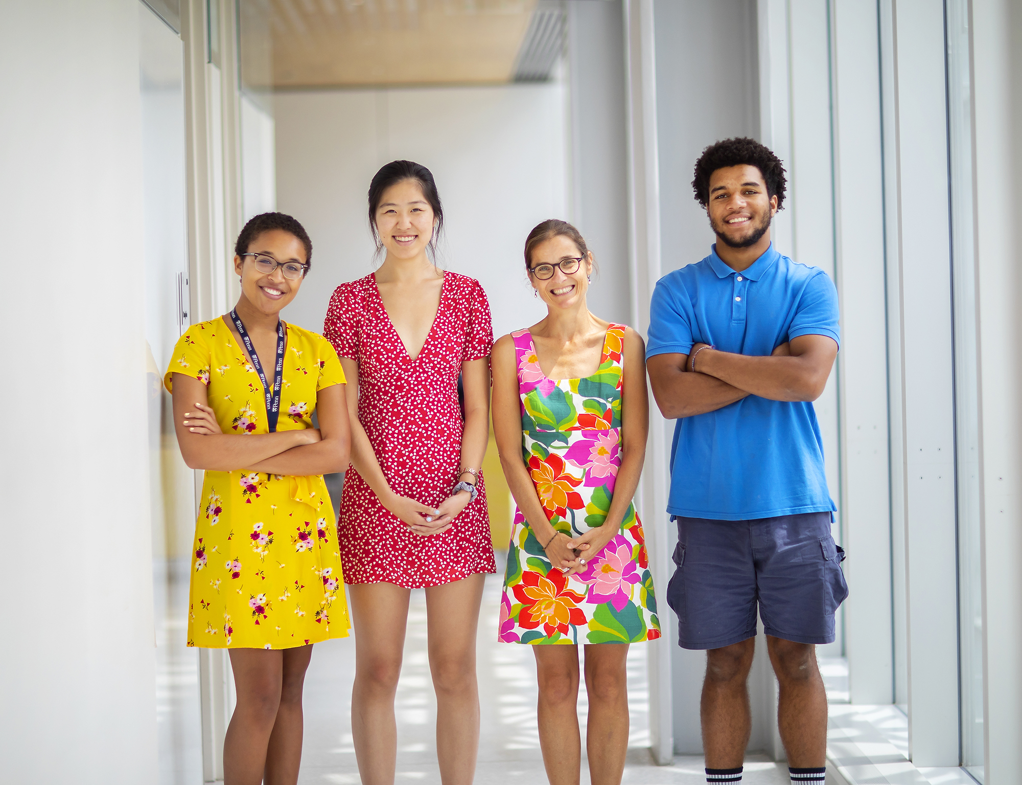 Four people in brightly colored clothing standing in a white hallway. 