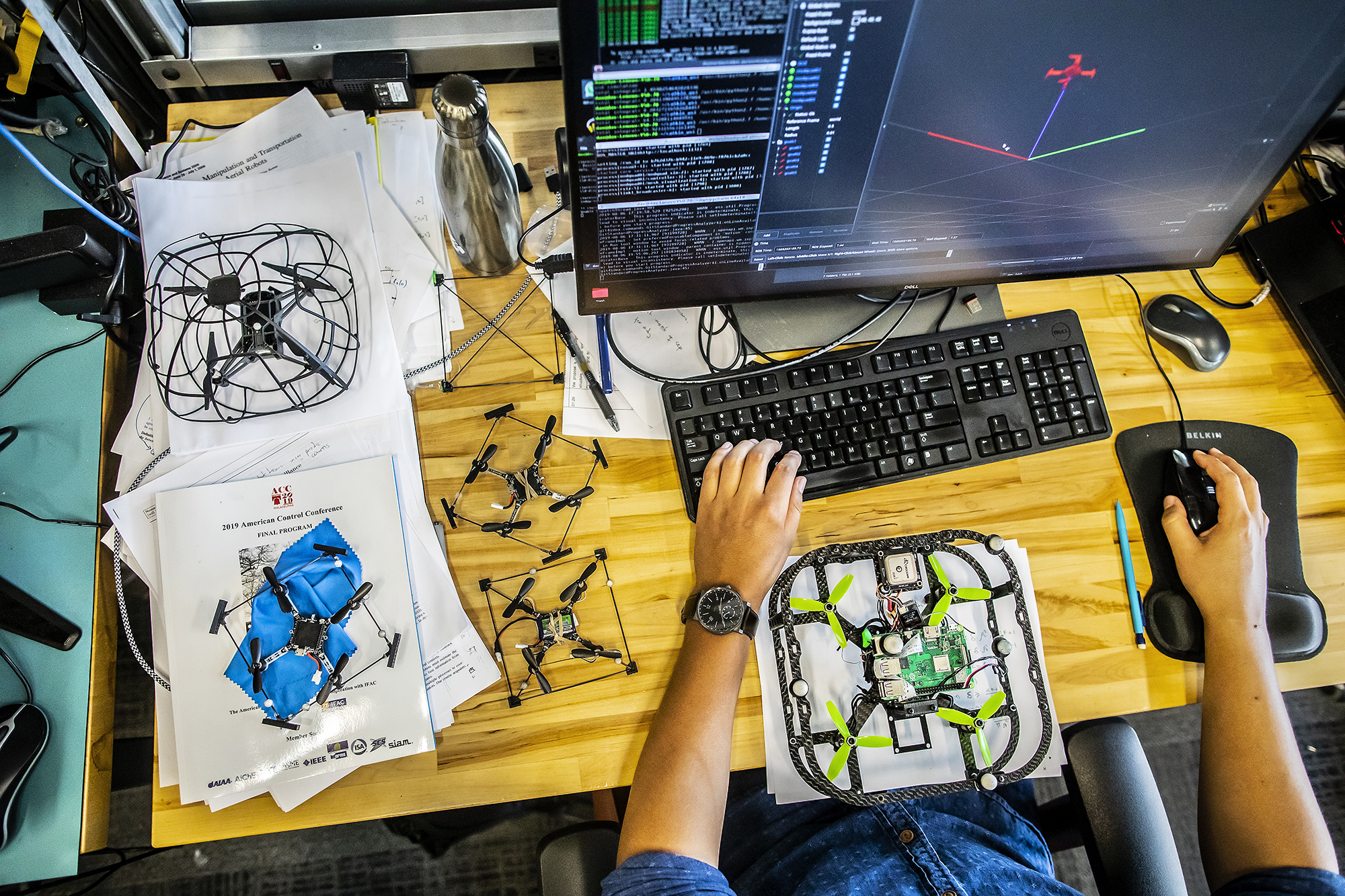 saldana working on a computer simulation of a drone surrounded by robot prototypes