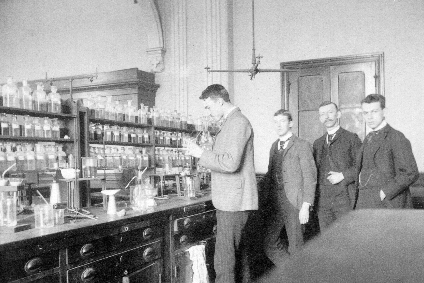 smith posing in a chemistry lab with three students