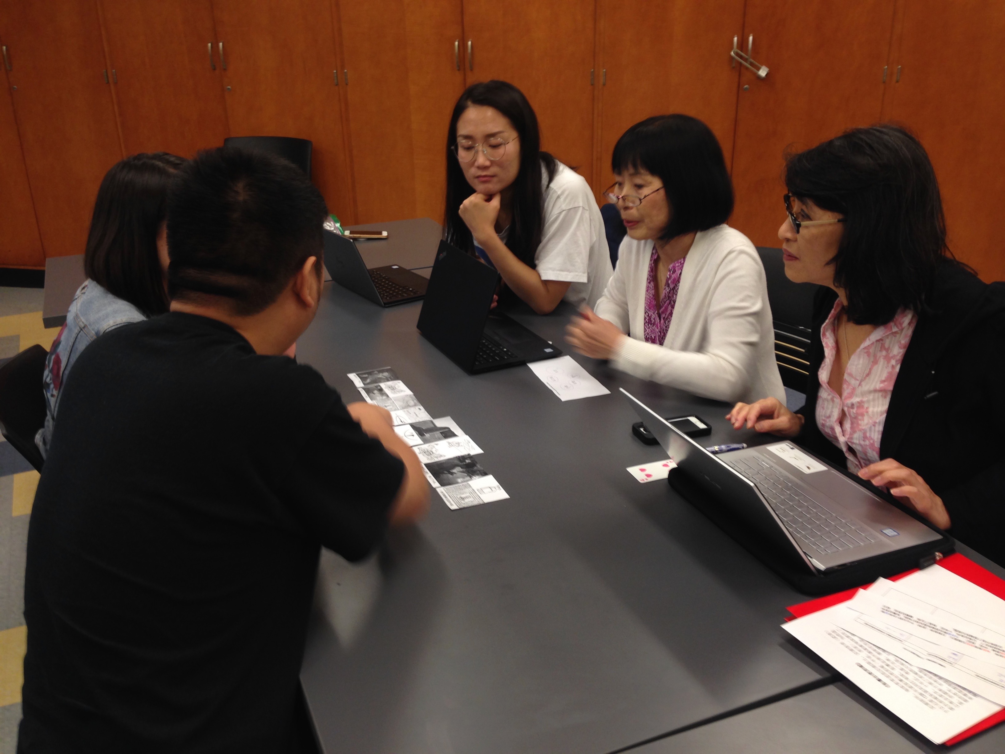 A group of people looking at photos on a table 