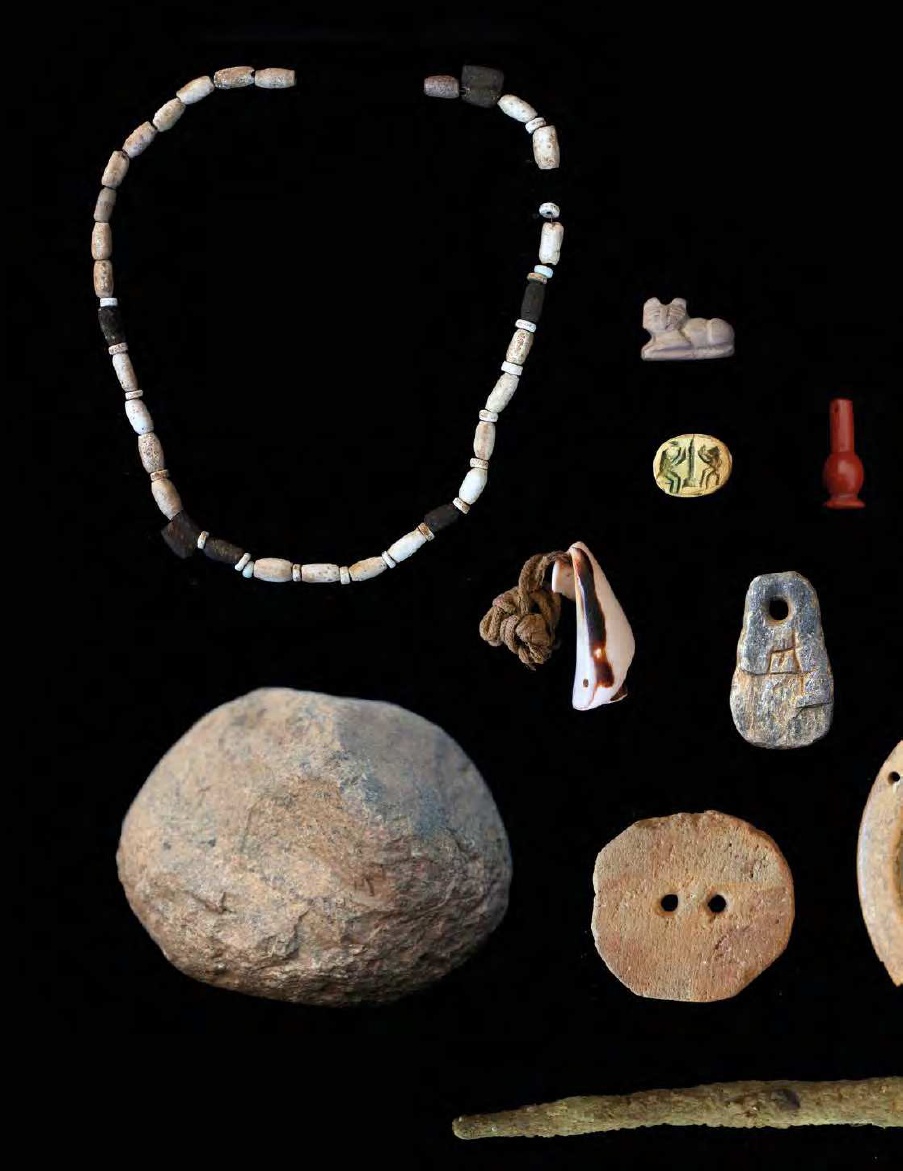 Necklaces and other pieces of ancient jewelry on a black background.