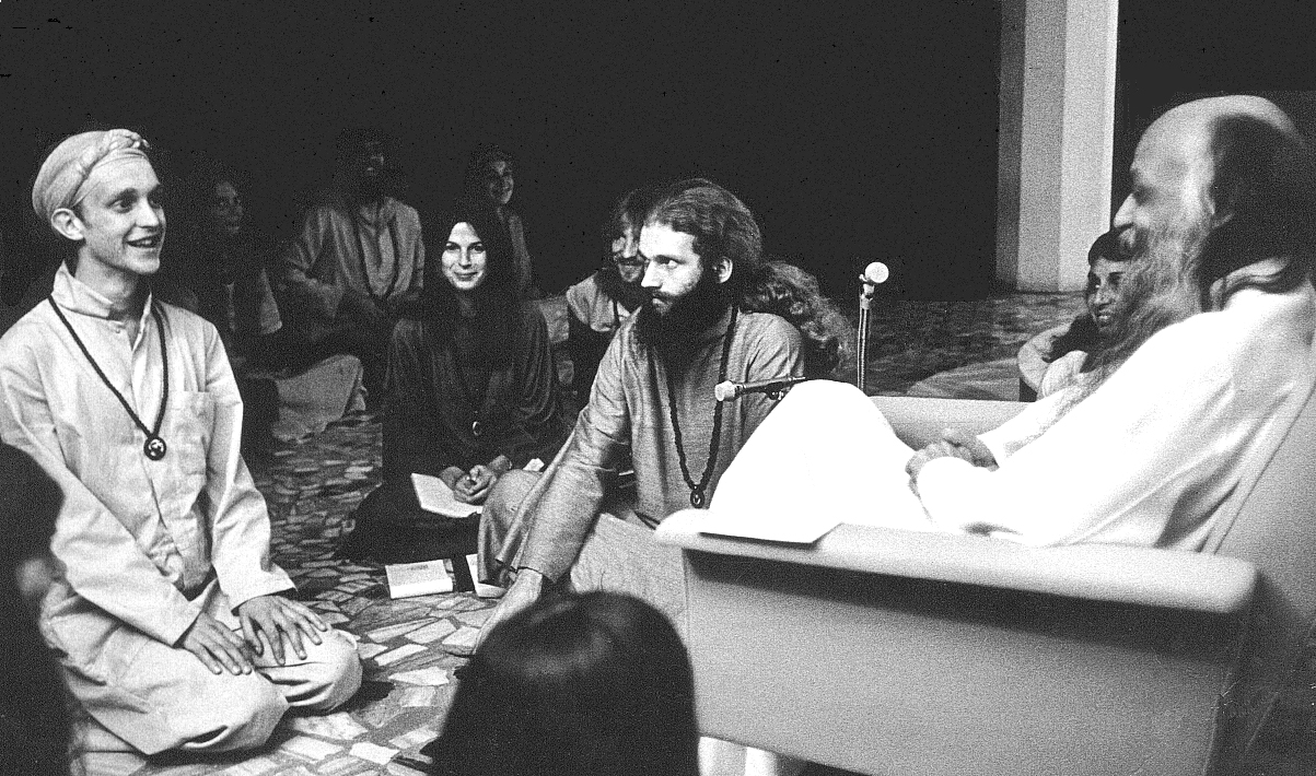 Osho seated with disciples kneeling before him, circa 1980s