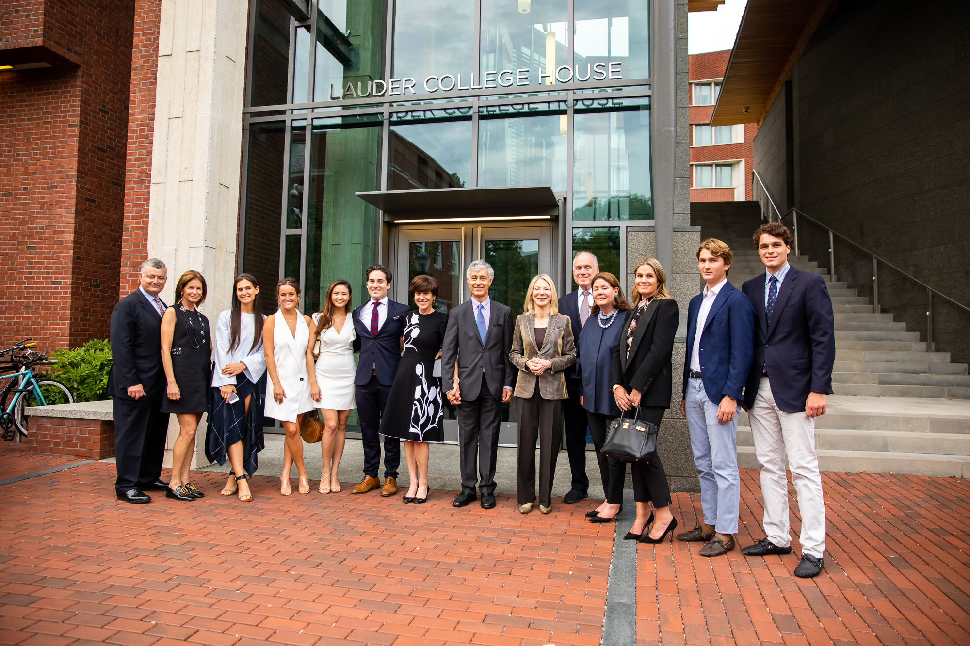 Several generations of Lauder Penn graduates and other family members join President Amy Gutmann in front of the new signage for Lauder College House.