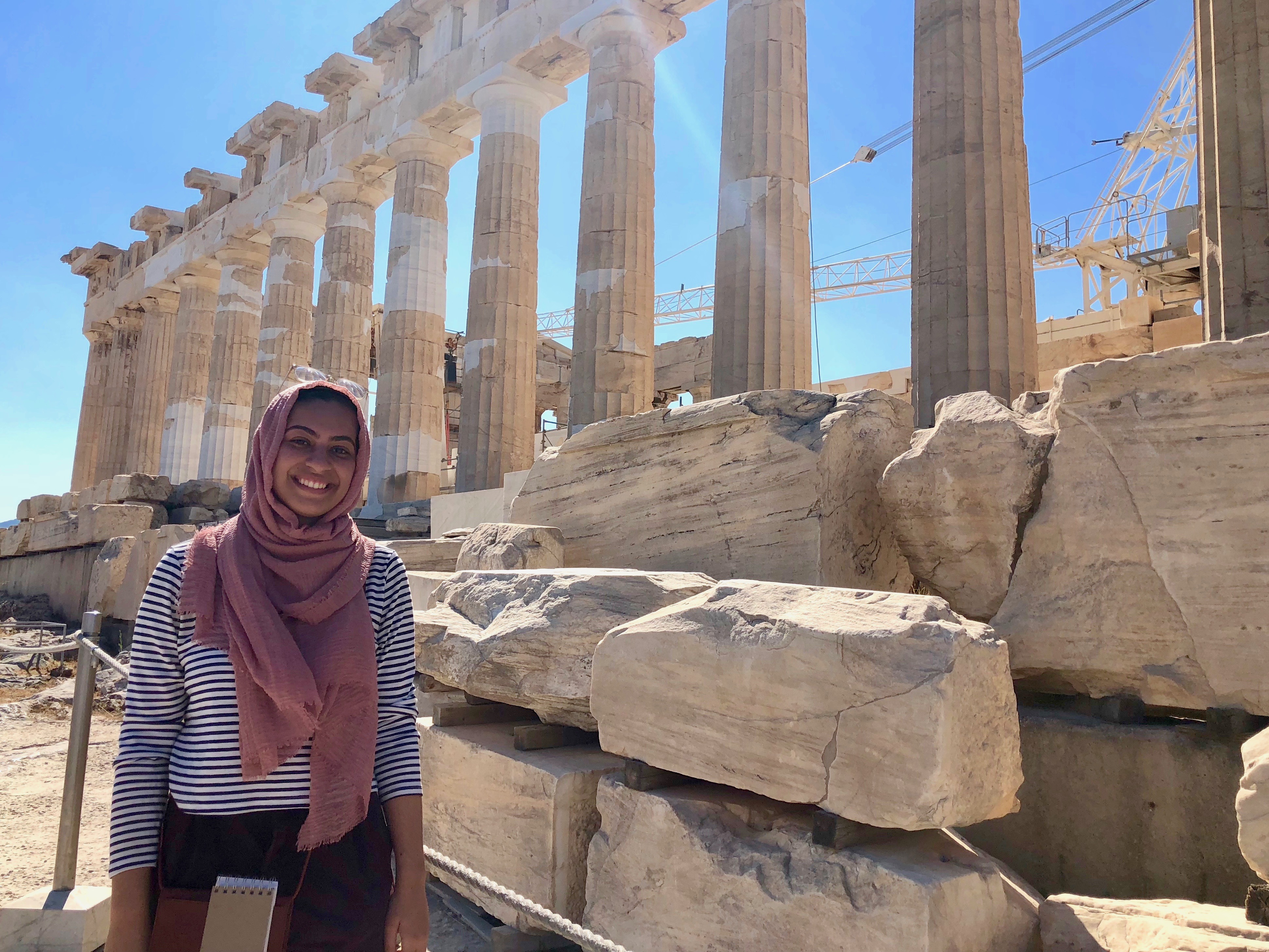 Students standing in front of a series of ancient columns and stones. 