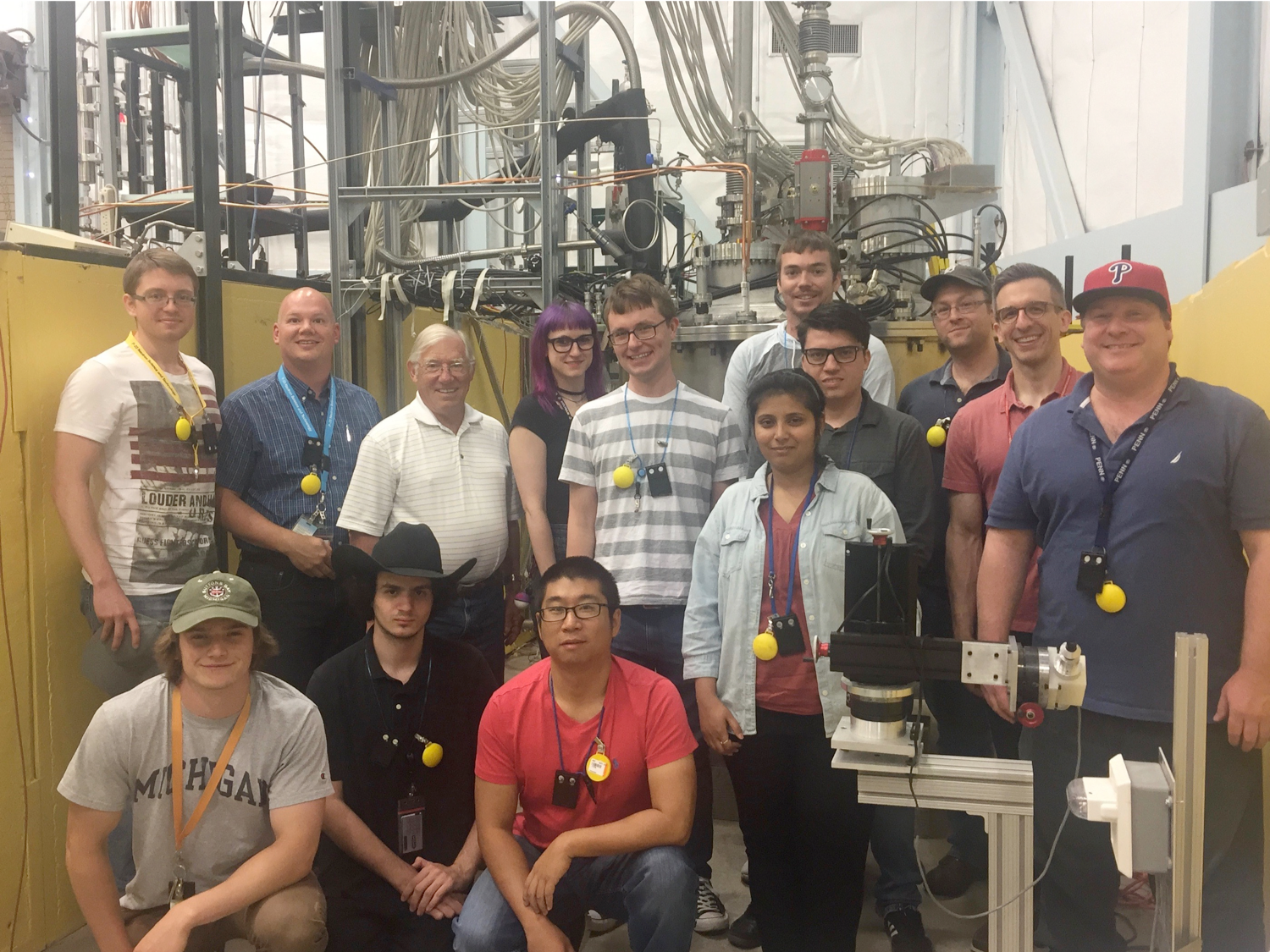 mauger at the far left standing with a group of students and post-docs in front of their prototype device in a lab