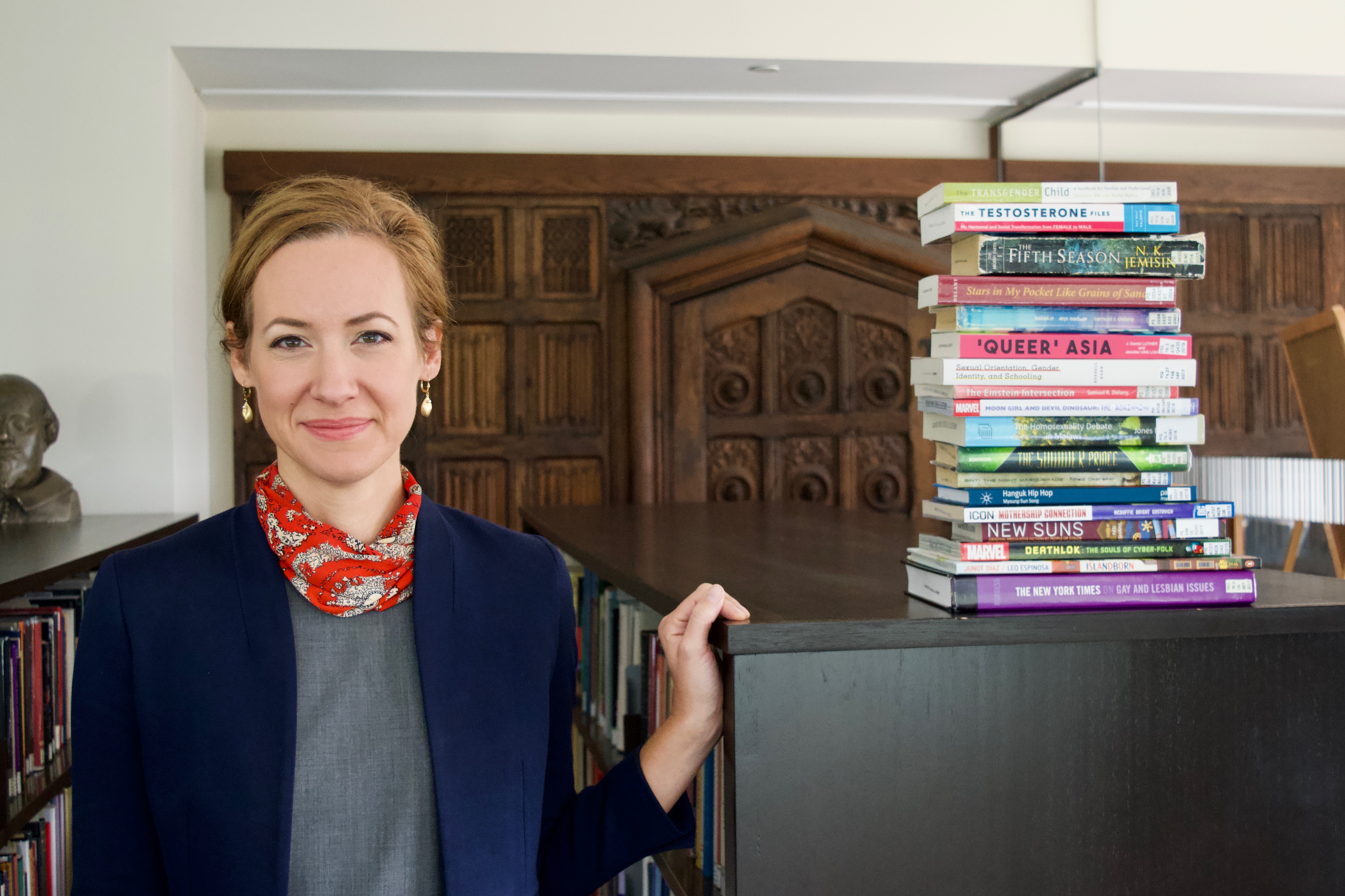 A librarian standing with a stack of books on a shelf. 