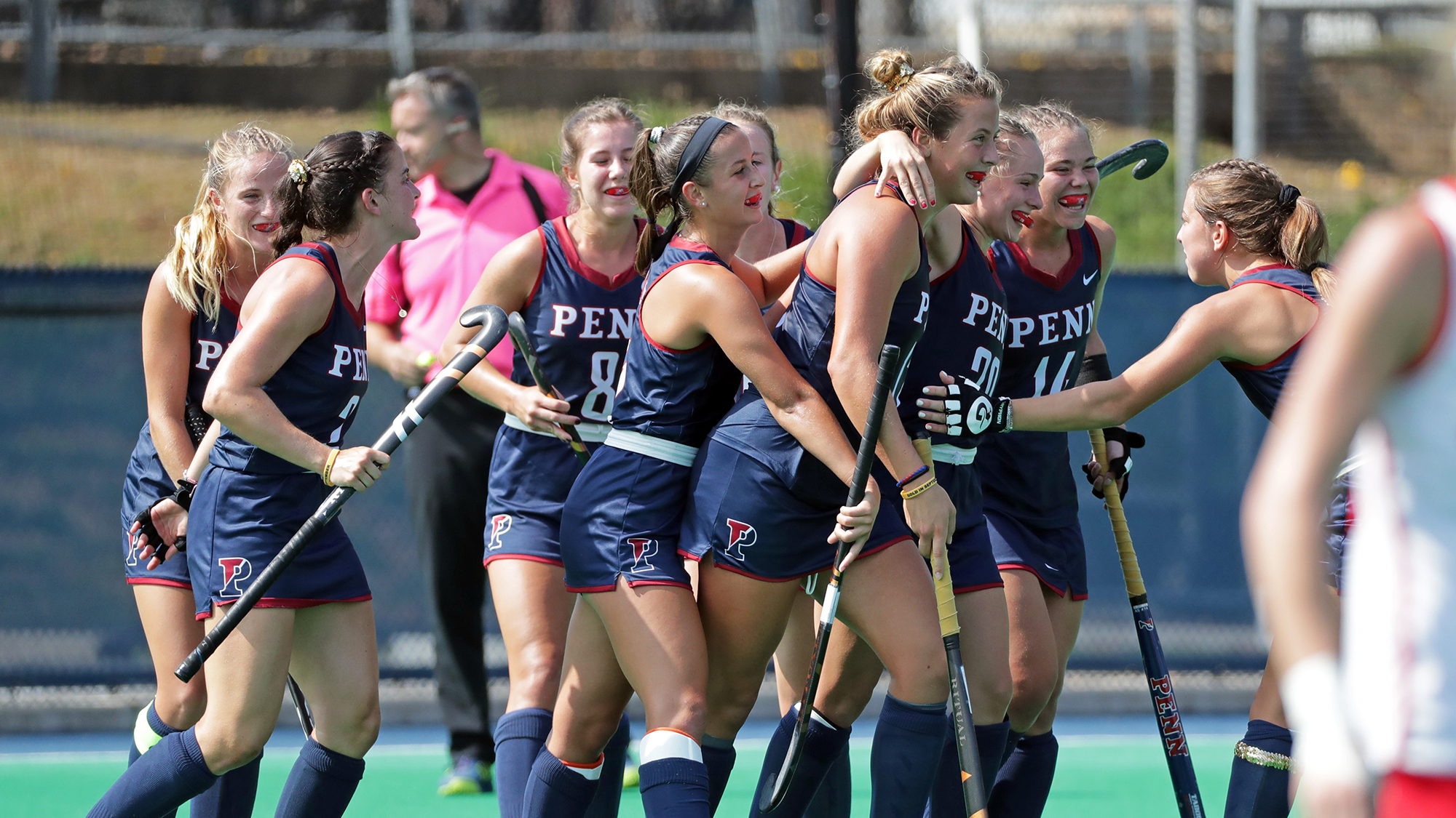 Members of the Field Hockey team celebrate in a circle.