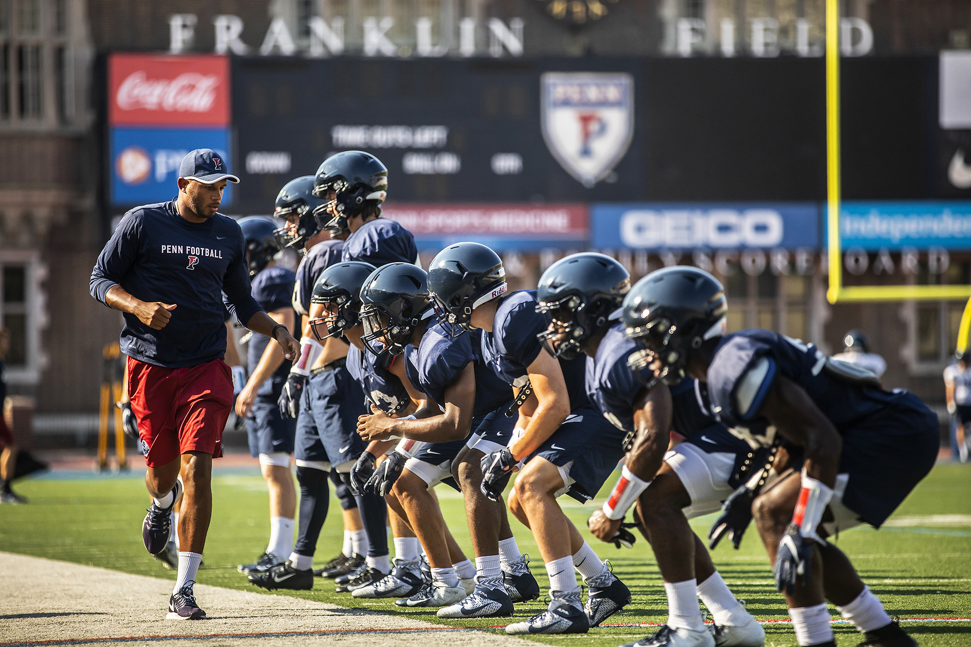 During preseason practice at Franklin Field, football players line up for a drill with their coach.