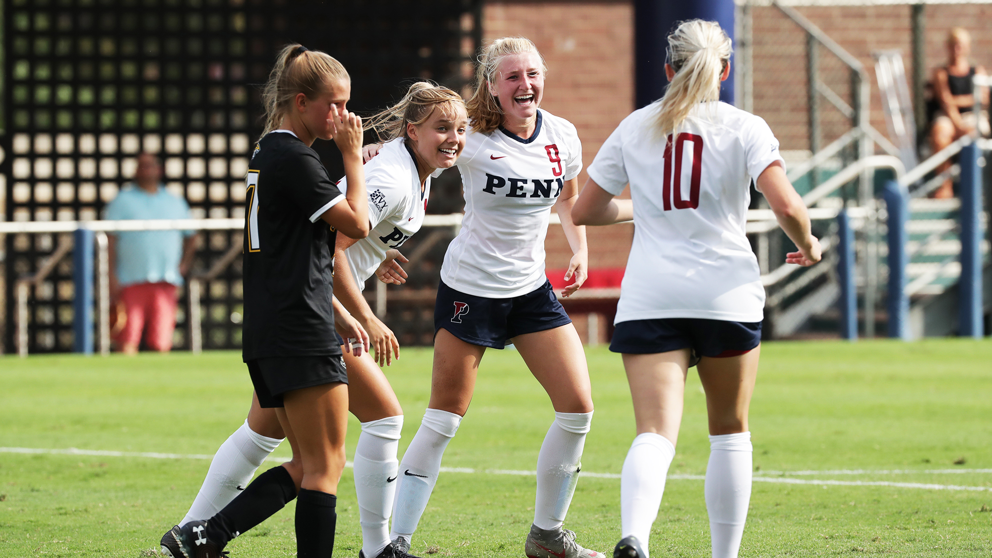 Three Penn women's soccer players celebrate on the field against Towson.