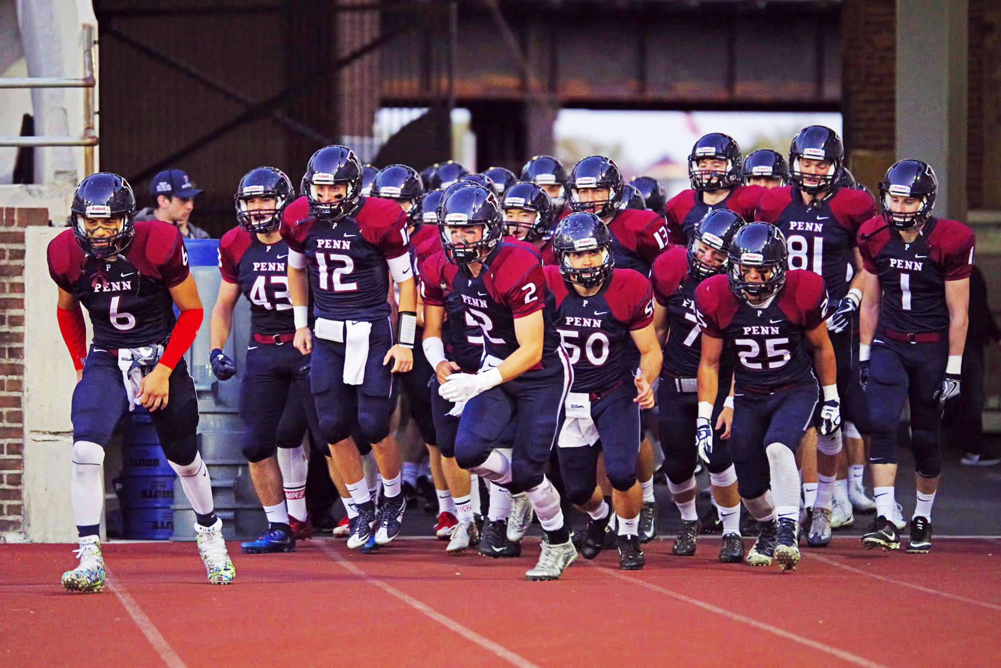 Members of the Penn sprint football team run out onto the field from the tunnel.