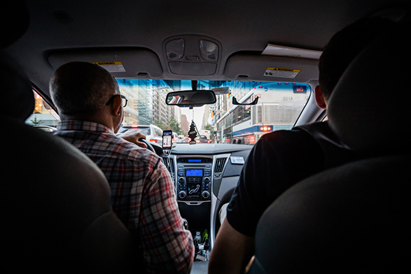 Uber or Lyft driver in traffic with a passenger in the backseat, view from backseat out the windshield