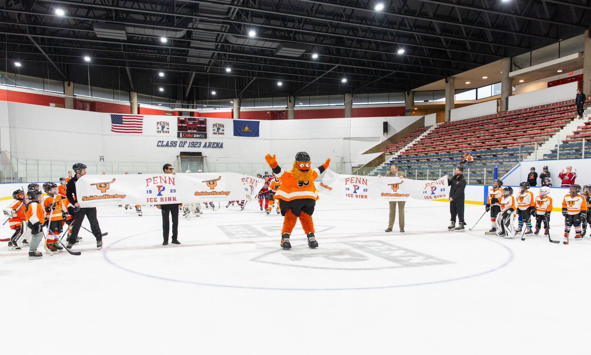 Philadelphia Flyers' mascot Gritty skates through ribbon at Penn Ice Rink.