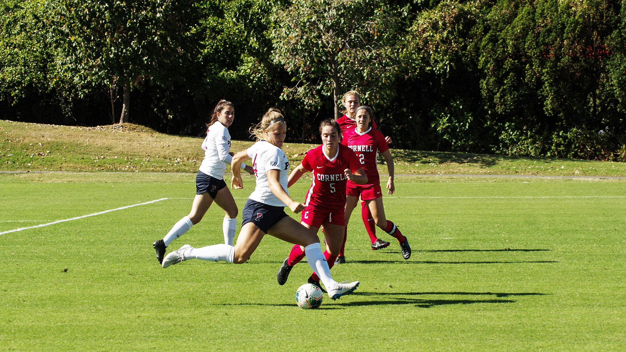 A member of the women's soccer team makes a move on a defender against Cornell.