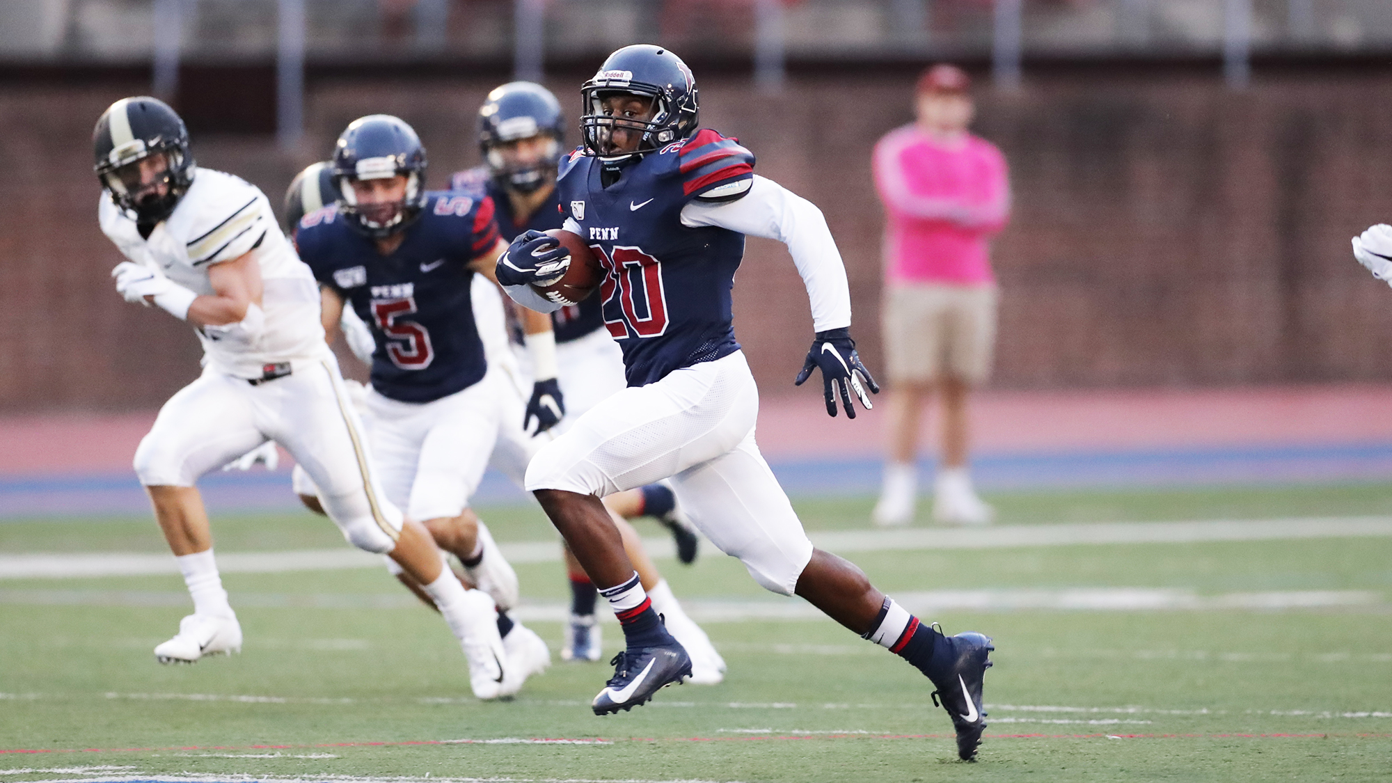 Laquan McKever of the sprint football team runs down the field while carrying the ball.