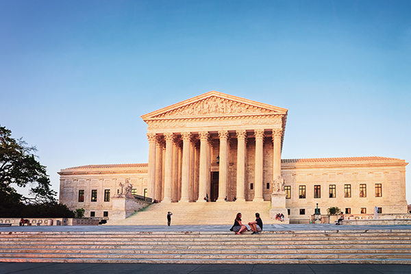 U.S. Supreme Court building with people sitting on the steps and others in the background