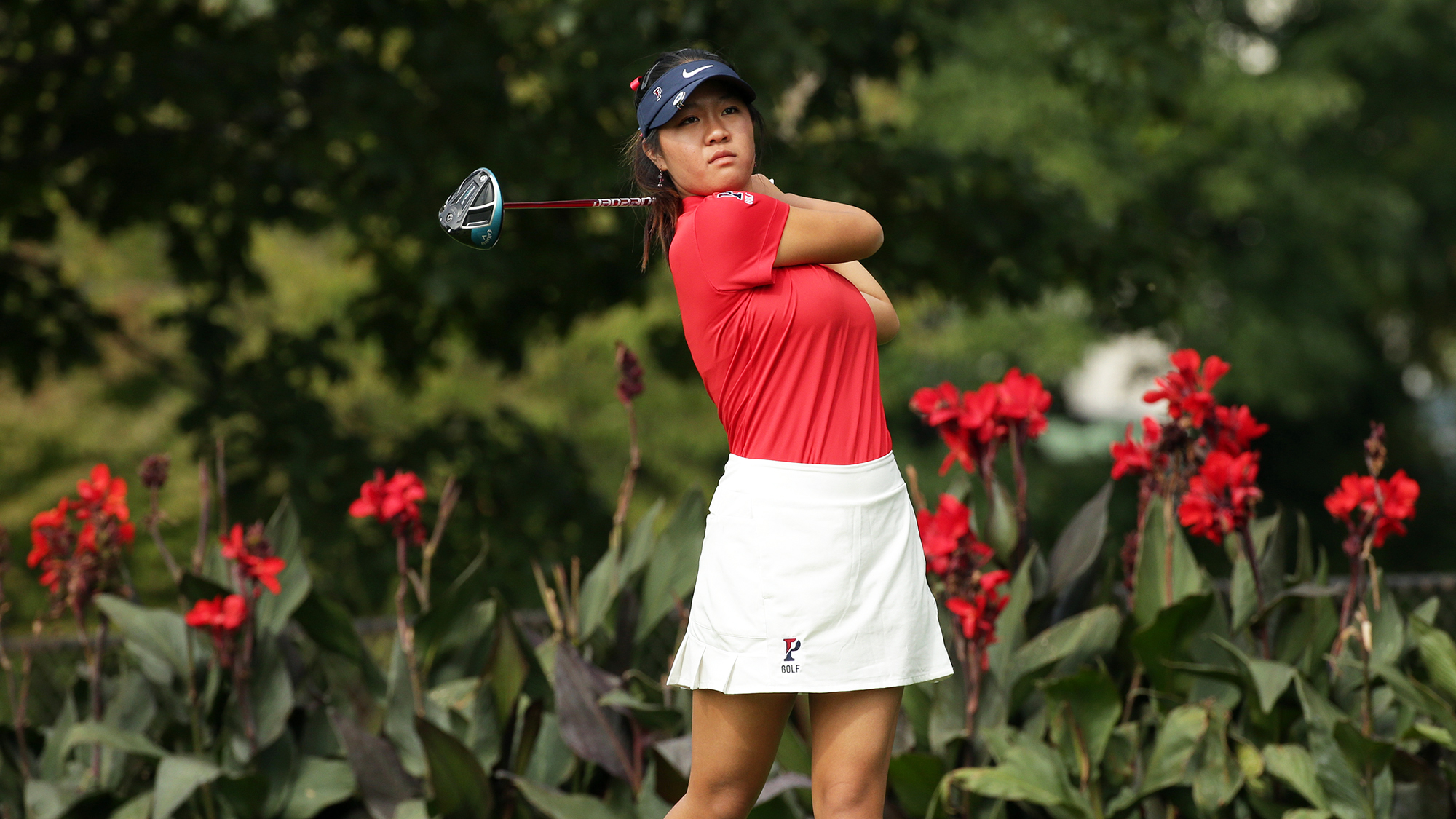 Susan Xiao of the women's golf team eyes the ball after completing her swing.