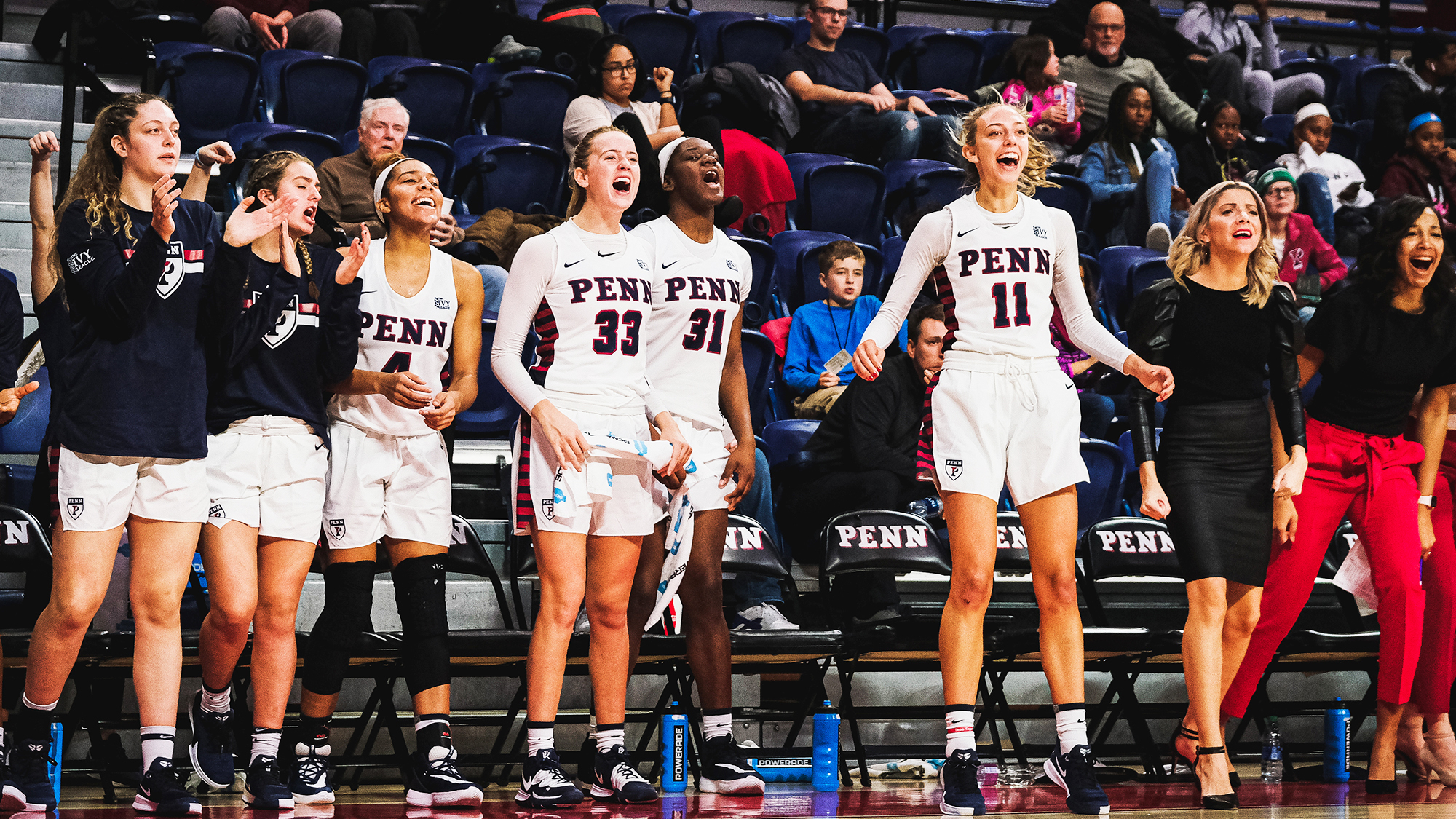 Members of the women's basketball team cheer on their teammates from the bench at the Palestra.