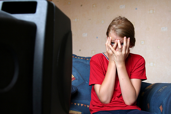 teenager watching television covers face with hands