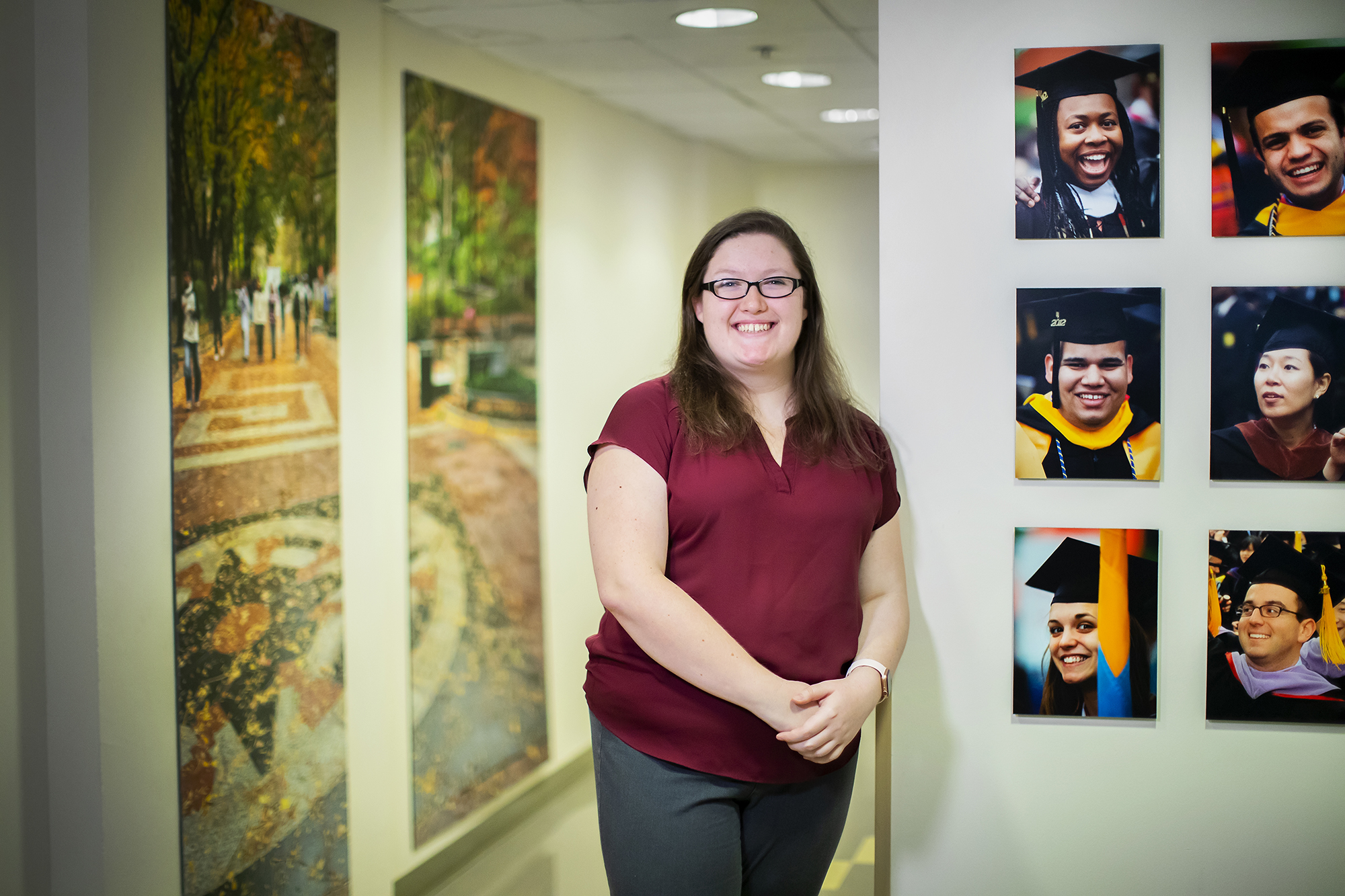Woman in glasses stands next to six images of students in graduation caps and gowns