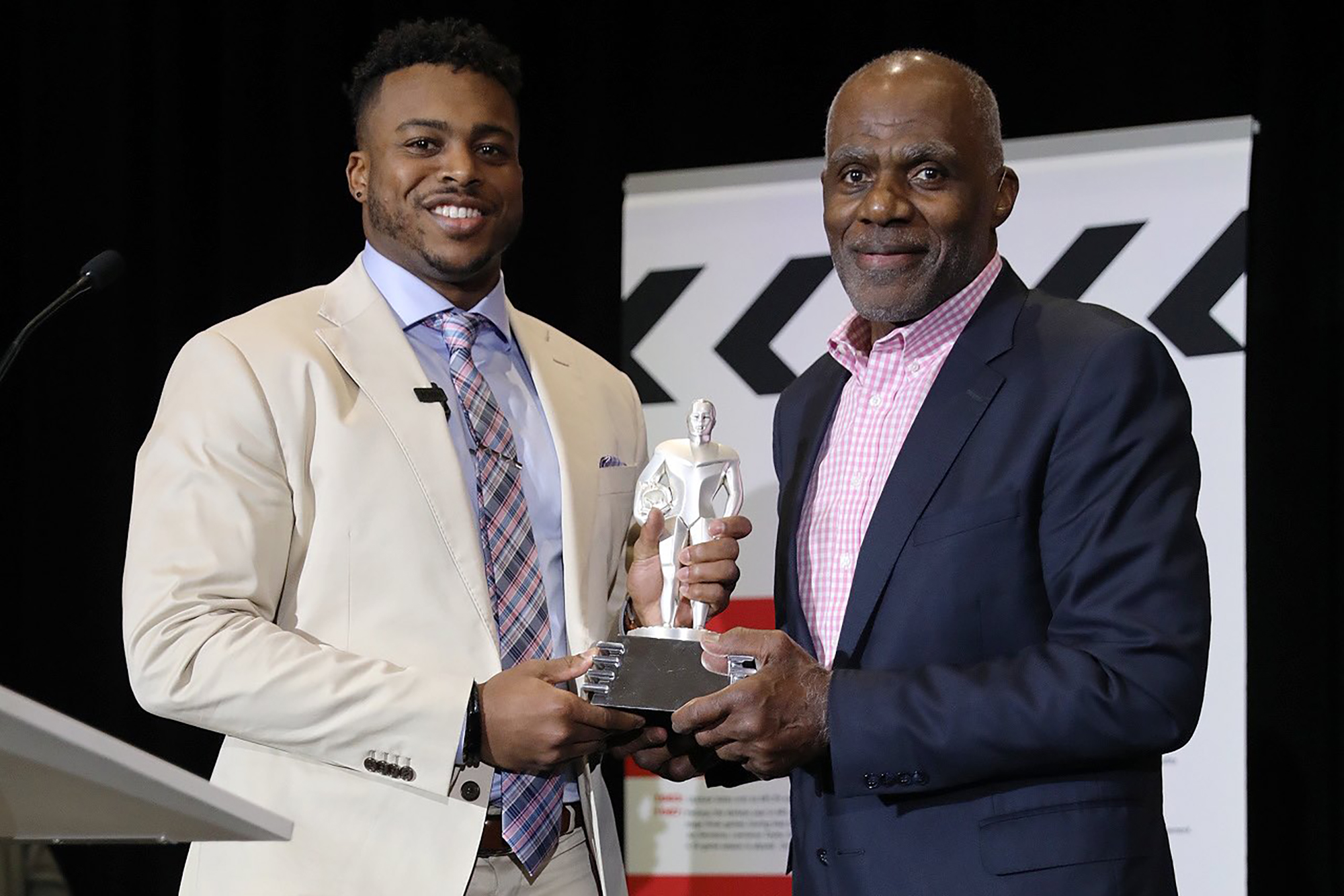 Brandon Copeland and Alan Page hold the NFLPA's Alan Page Community Service Award on stage.