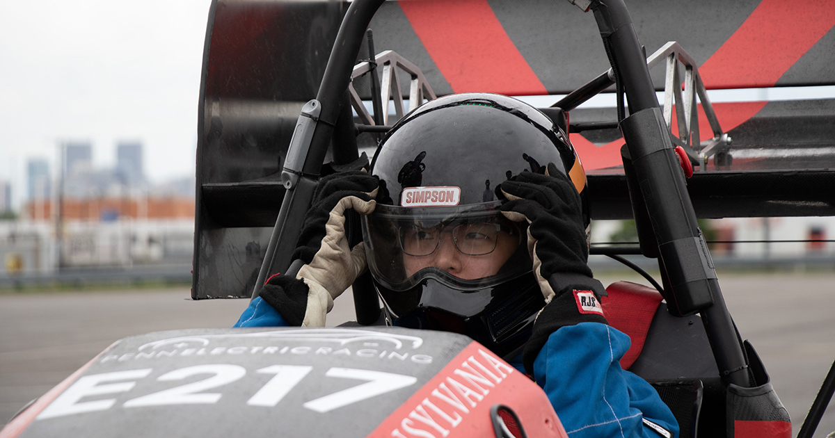 Kathie Jin adjusts her helmet inside a Penn Electric Racing car.