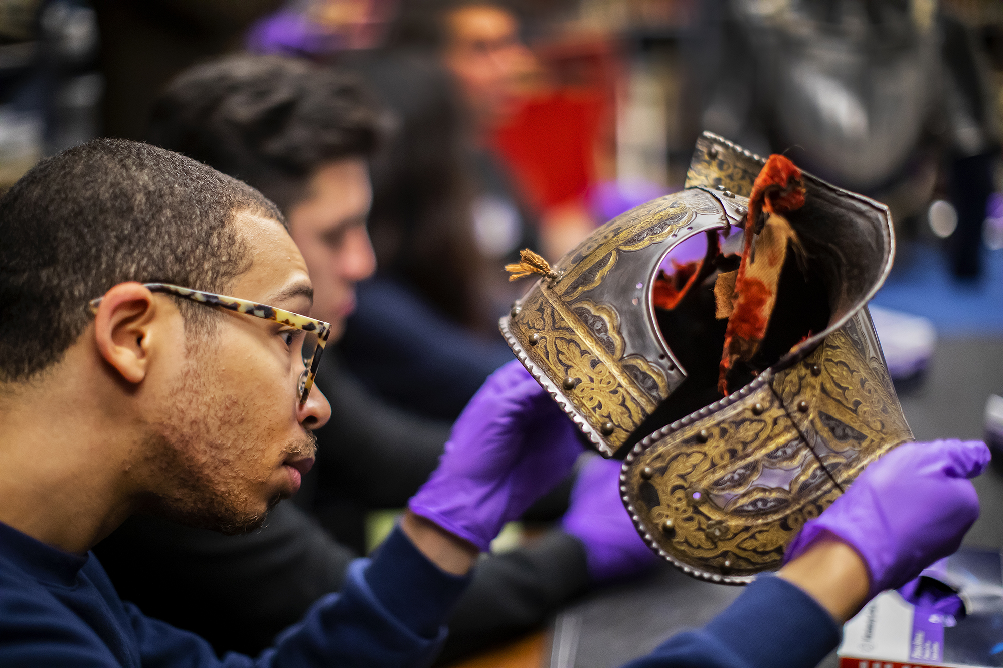 a student taking a close look at a piece of armor