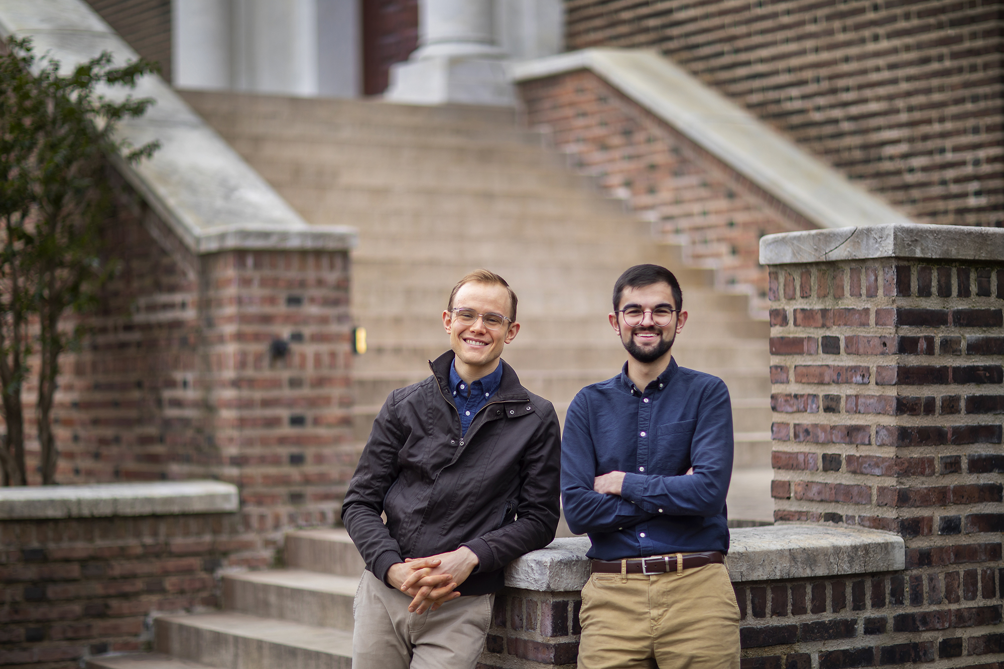 Two men stand in front of the brick and stone stairway leading to the Penn Museum