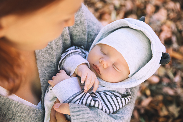 person holding a newborn baby outside in the autumn