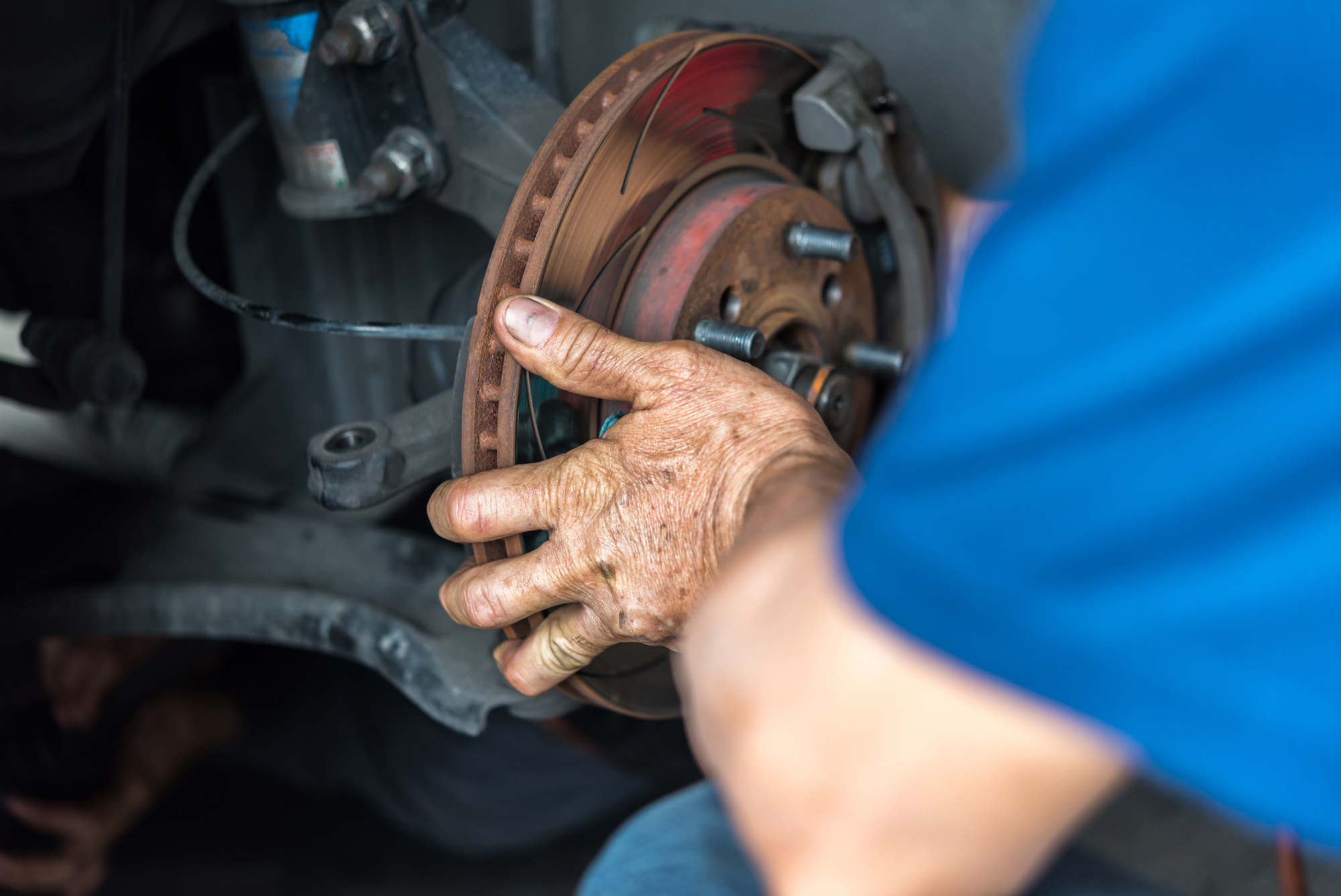 A car mechanic works on a brake pad.