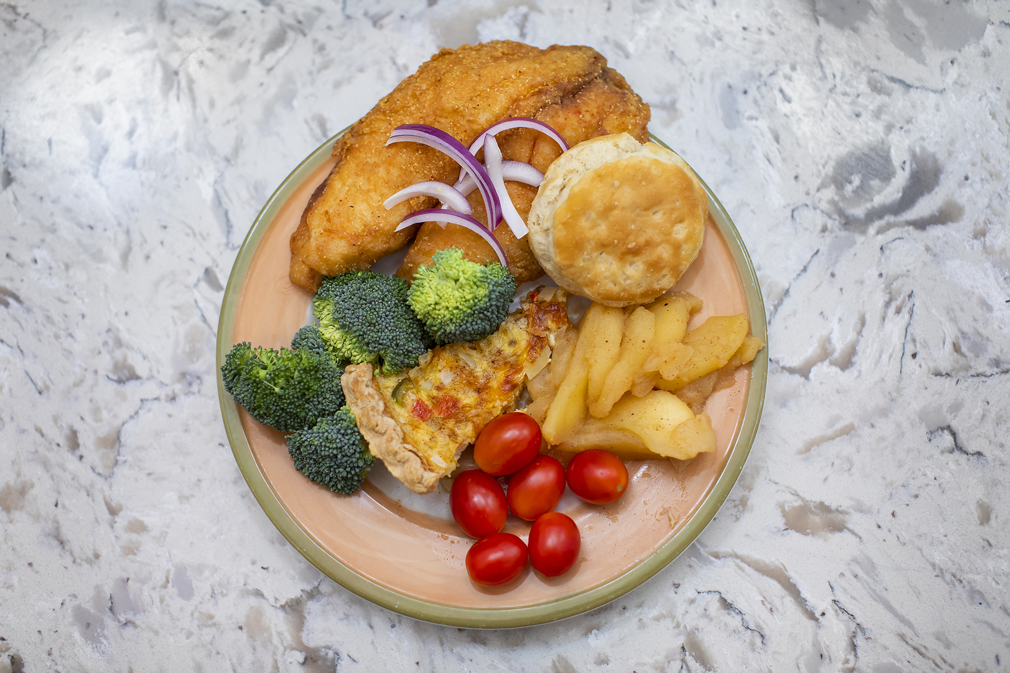 Plate of food which includes fried fish, crab pie, butter biscuit and roasted apples.