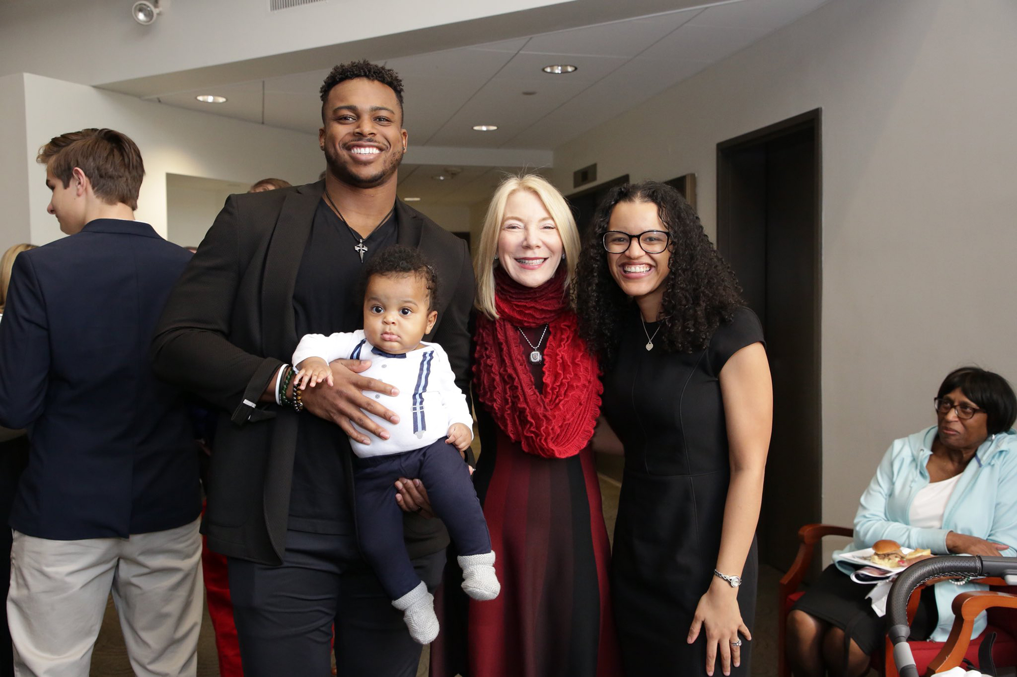 Brandon Copeland, holding his son, with Penn President Amy Gutmann and his wife Taylor Copeland.