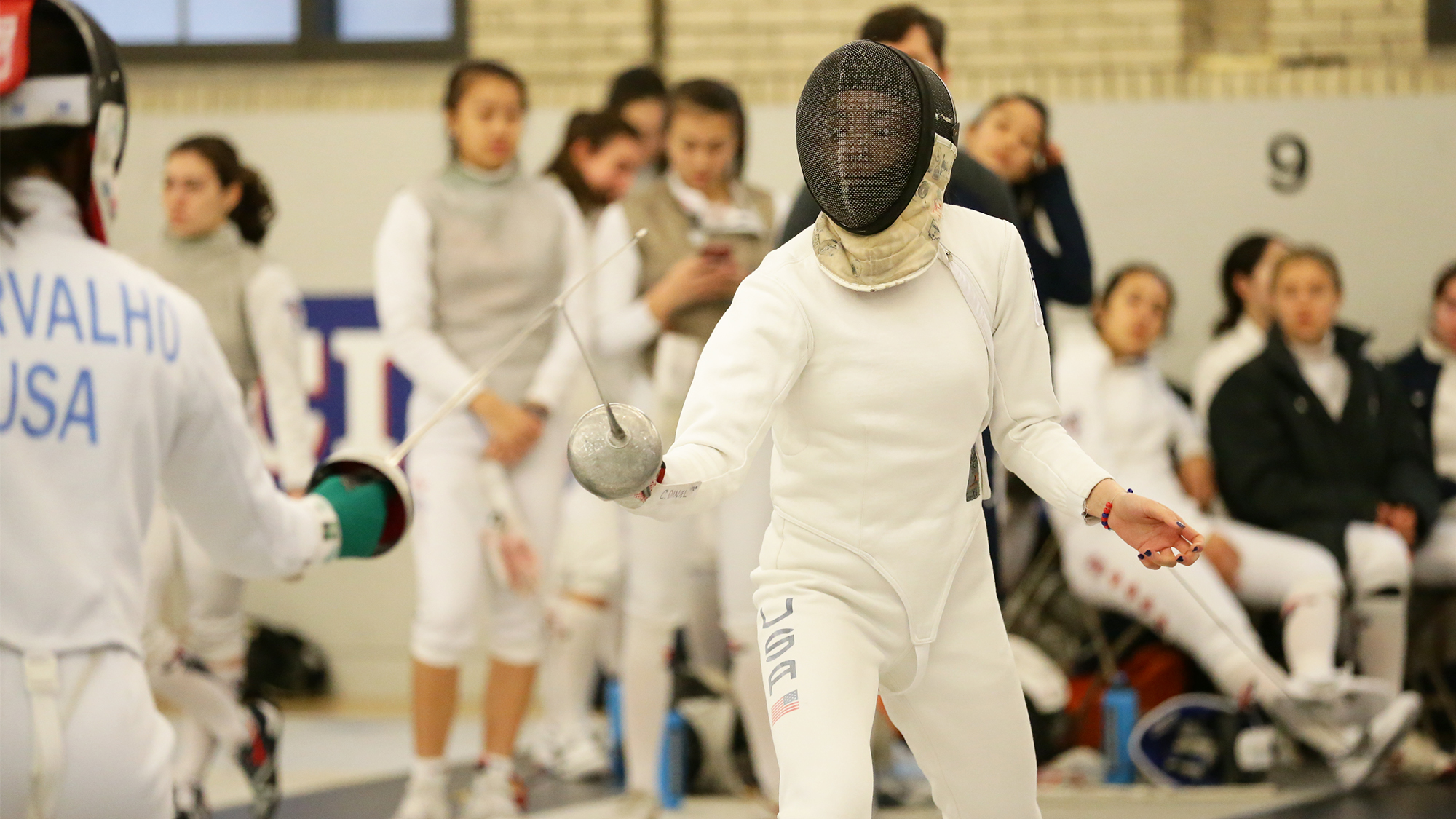 Freshman Chloe Daniel competes in a fencing duel while wearing protective clothing and holding her sword.