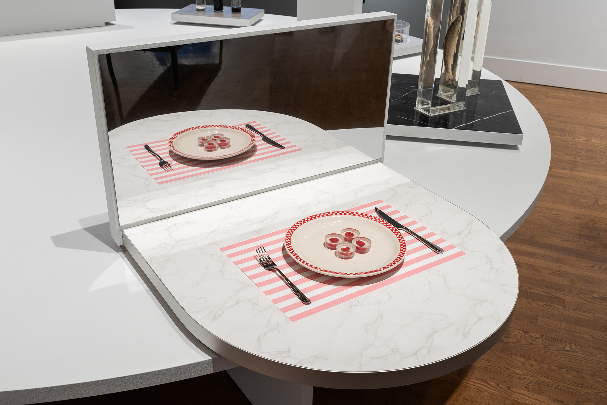  Plate of four pieces of faux steak on a placemat with a fork and knife on a marble surface at the Designs for Different Futures exhibit.