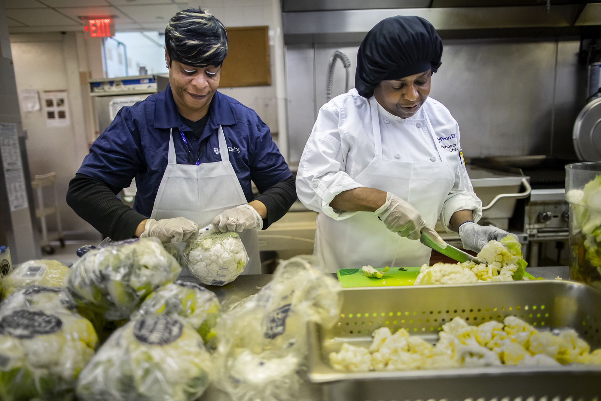 Chefs cutting bags of cauliflower in the kitchen of the dining hall at Penn.