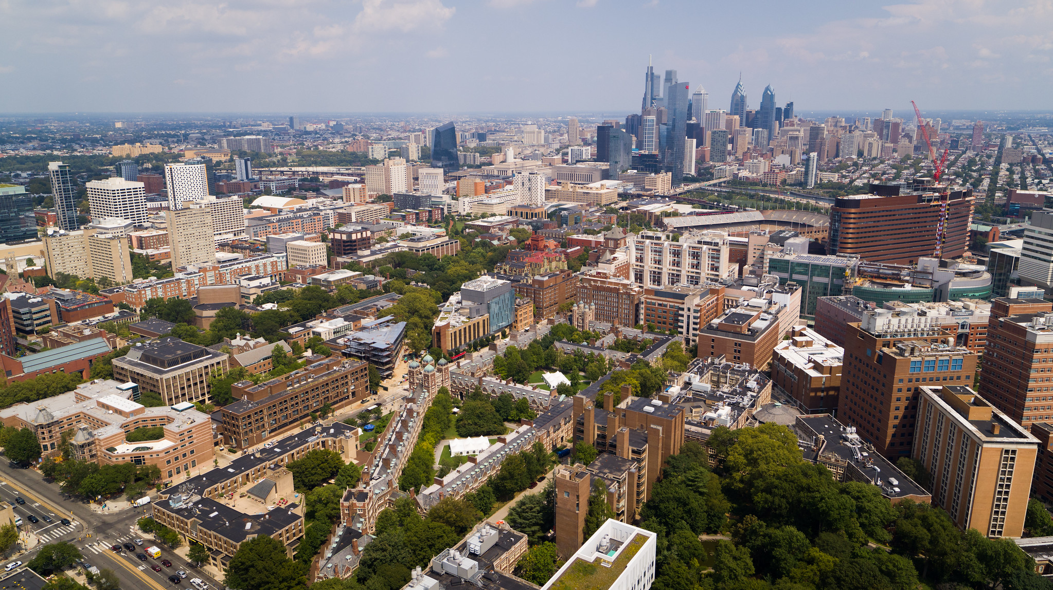 Aerial view of Penn campus buildings with Philadelphia skyline in background.