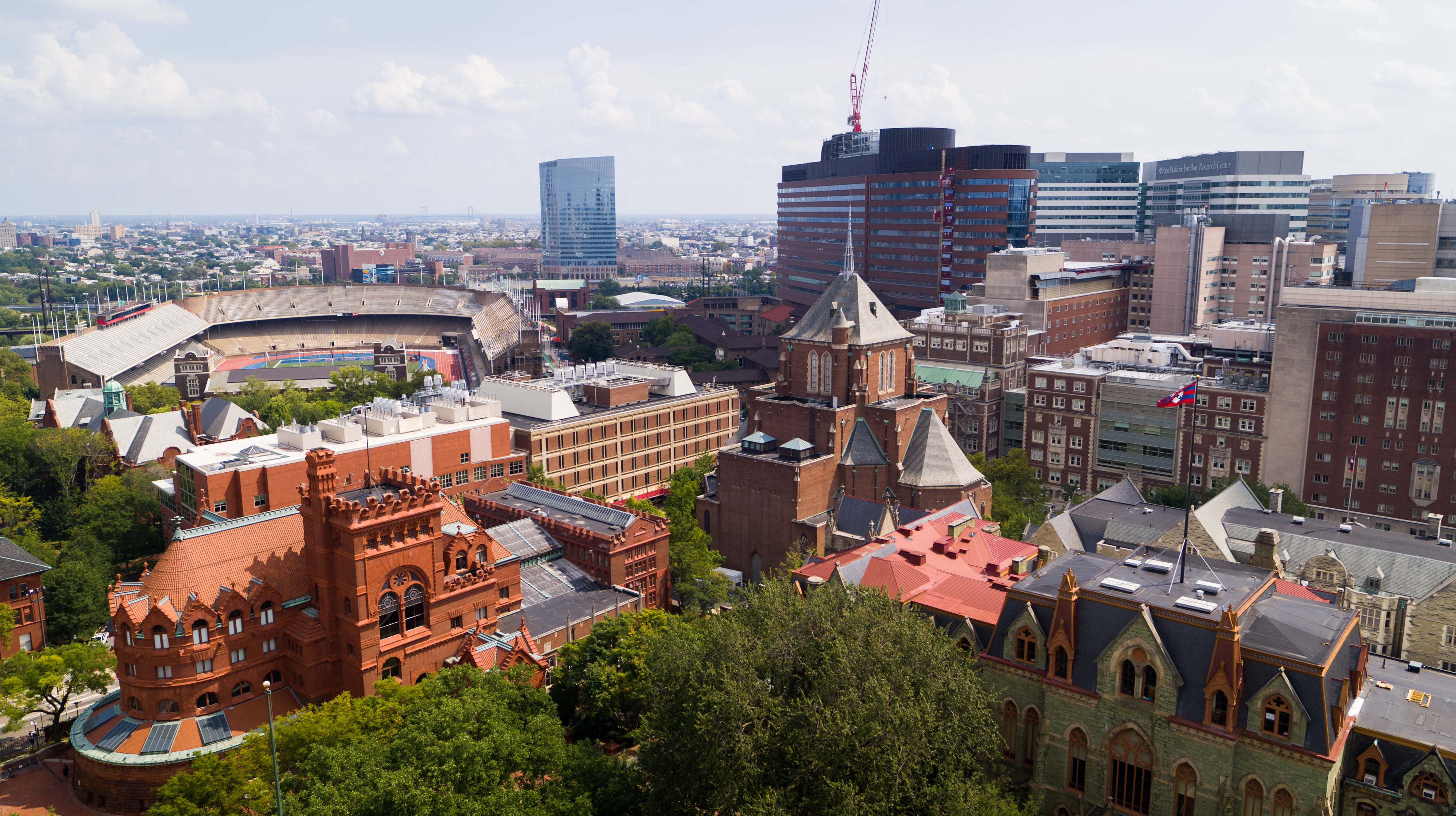 aerial view of campus in daylight, college hall in foreground, palestra and penn med in background, philadelphia city skyline in distance