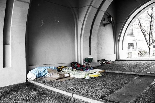 Bedding and blankets belonging to homeless people on the ground underneath an underpass