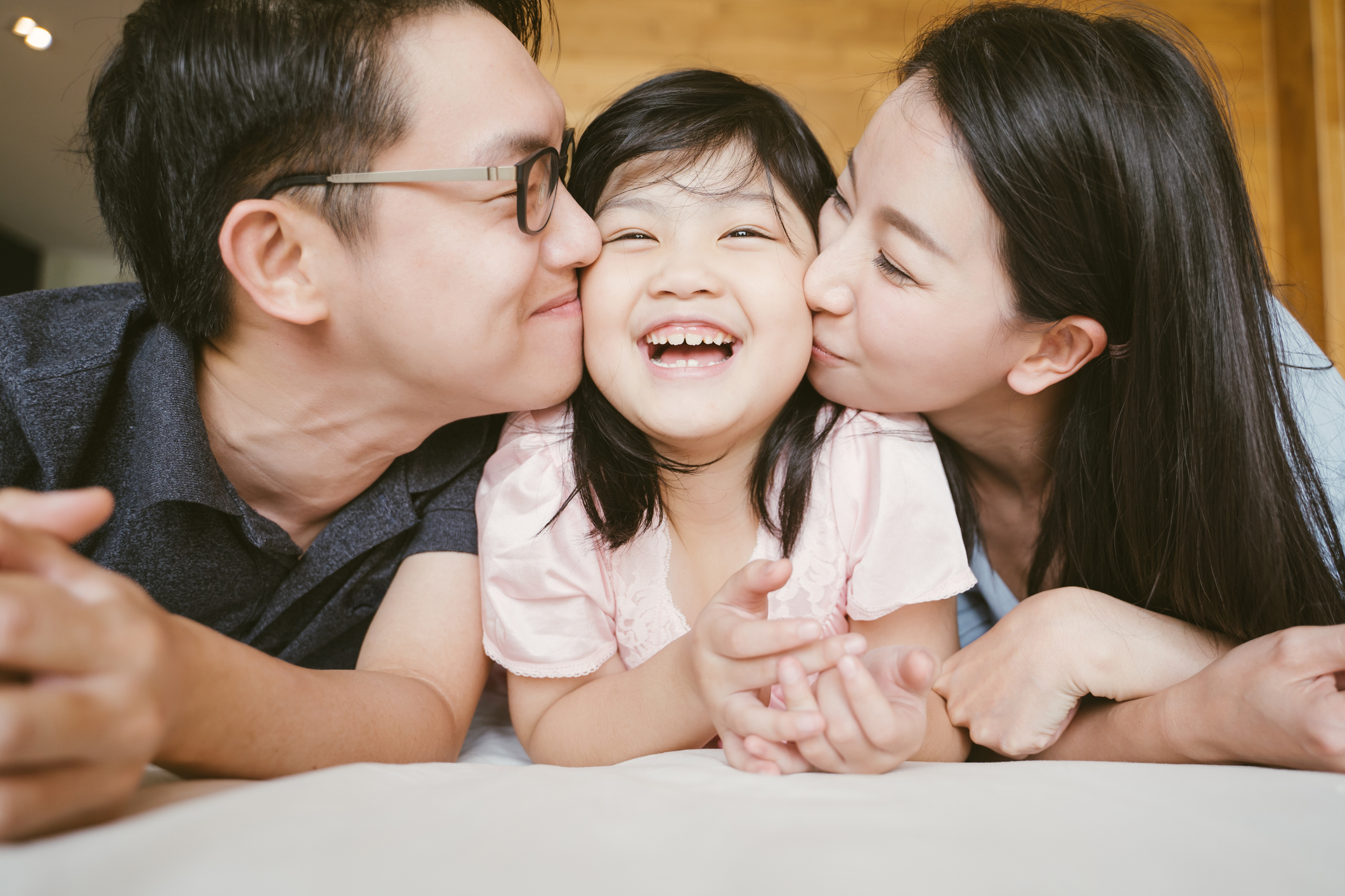 Two Asian parents kiss their child