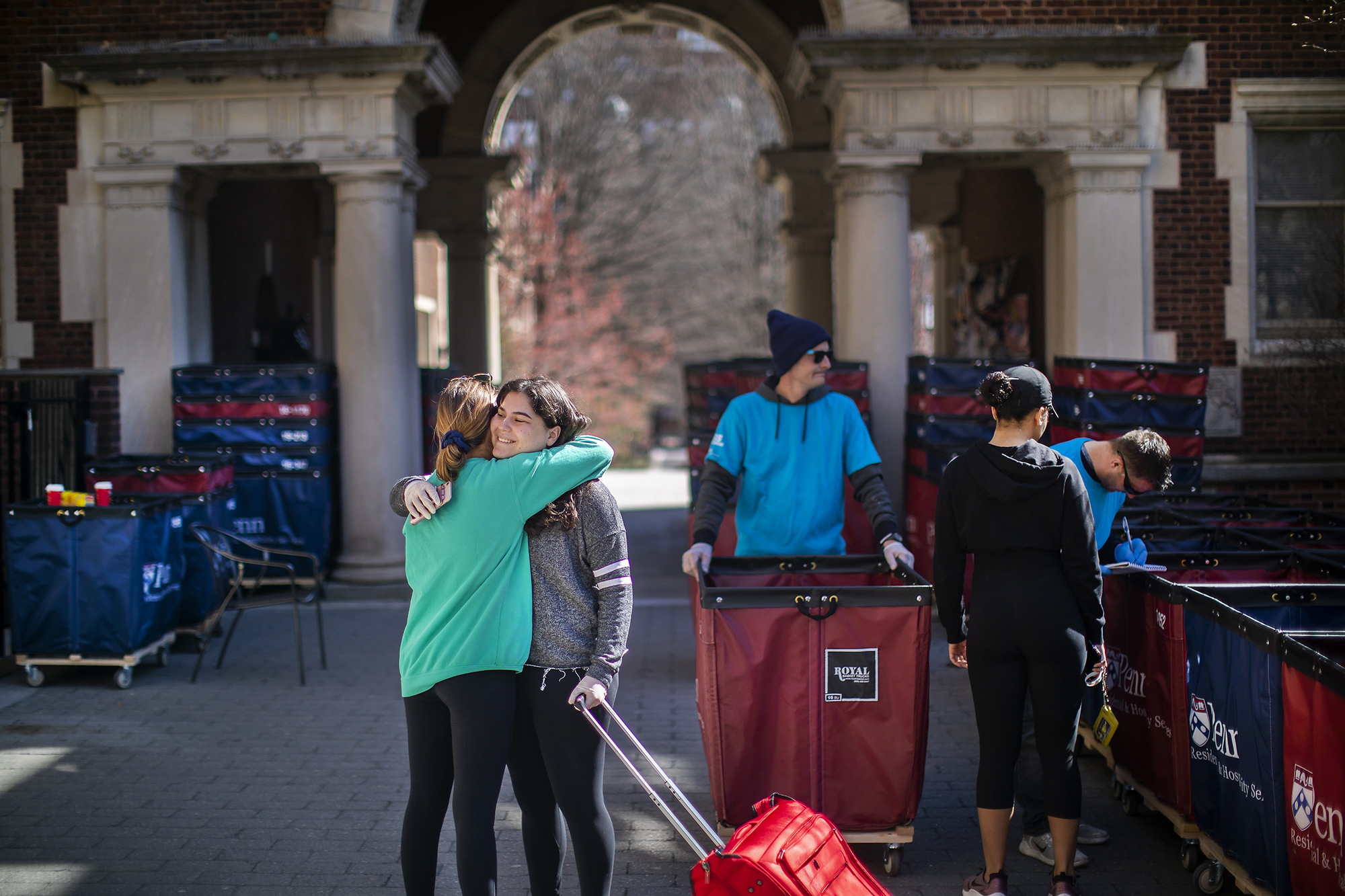 Two students embrace on the Quad amidst move-out carts