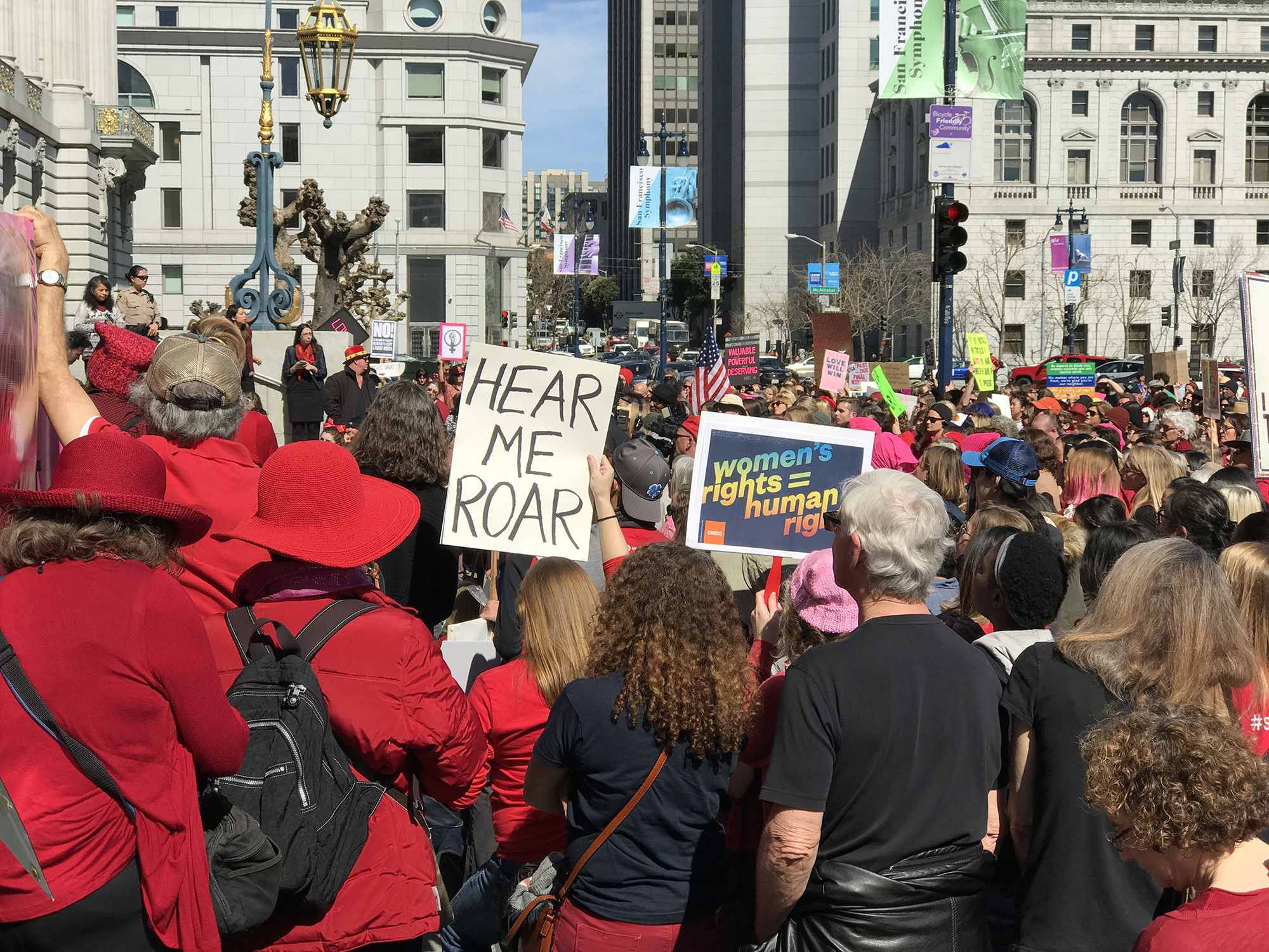 International Women's Day rally in San Francisco, one person holds a sing reading "Hear Me Roar" and another sign reads "Women's rights equals human rights."