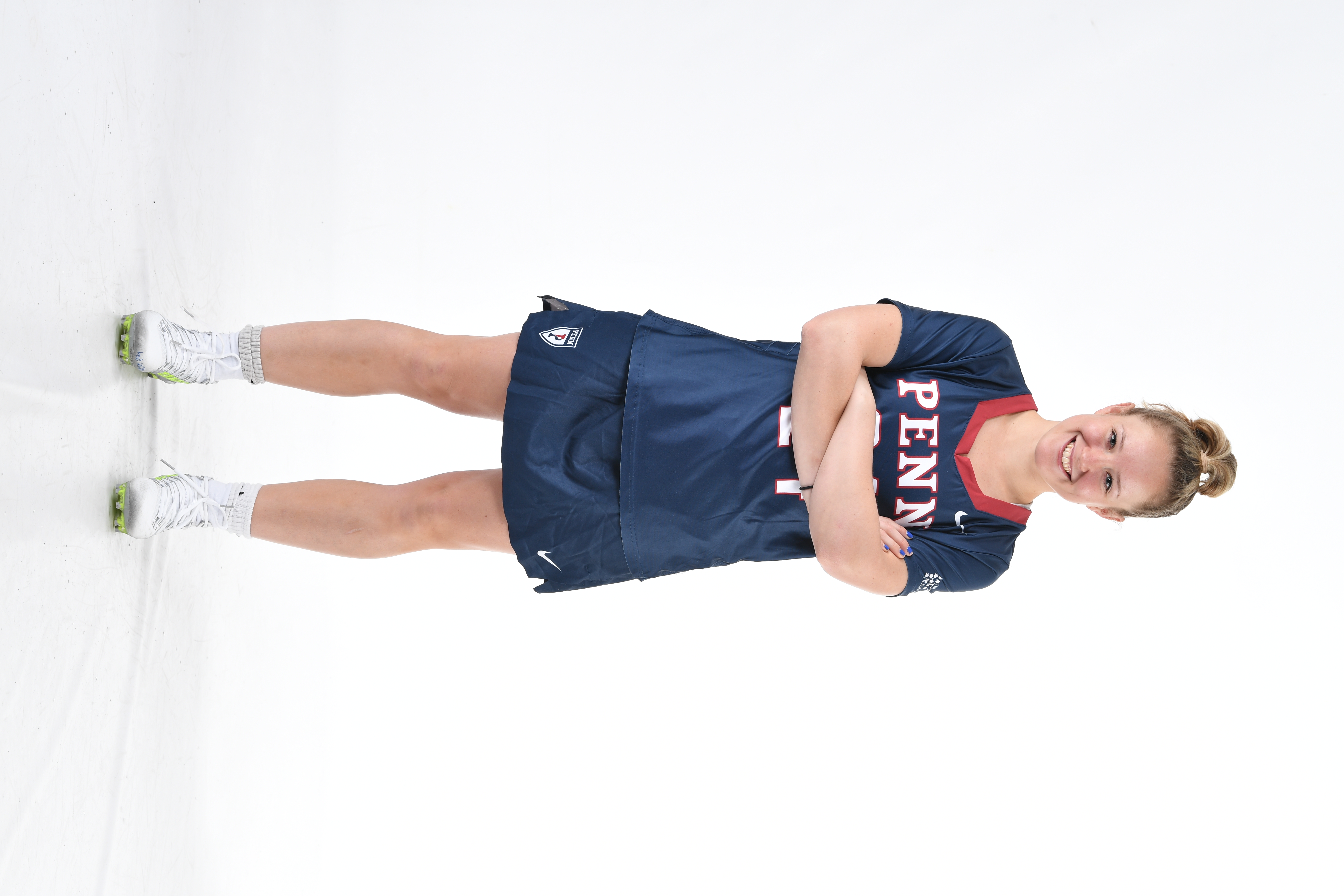 A portrait of Gabby Rosenzweig in her dress lacrosse uniform with her arms folded.